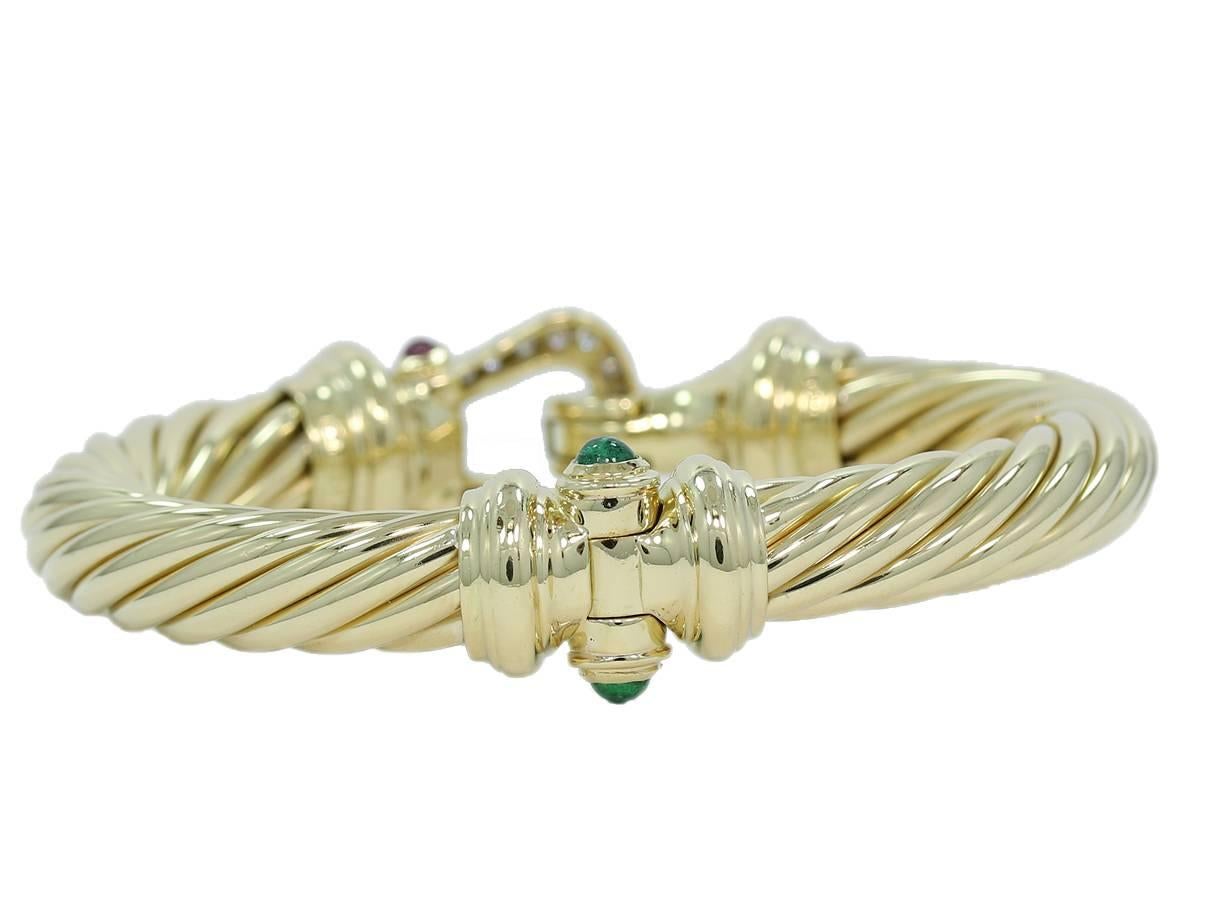 This is a large David Yurman Cable Classic Buckle Bracelet with Diamonds, Emeralds and Rubies in 18k yellow gold. The Bracelet has approximately .46cts of round brilliant cut diamonds that make up the buckle clasp. On both sides of the clasp is a