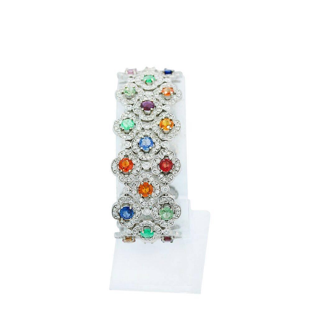 We have this beautiful 14k white gold flat wide bracelet with diamonds and color stones. The diamonds weigh 10.05 carats total weight and the color stones 12.55 carats total weight. The bracelet measures 7.25" in length x 1.00 inch in width