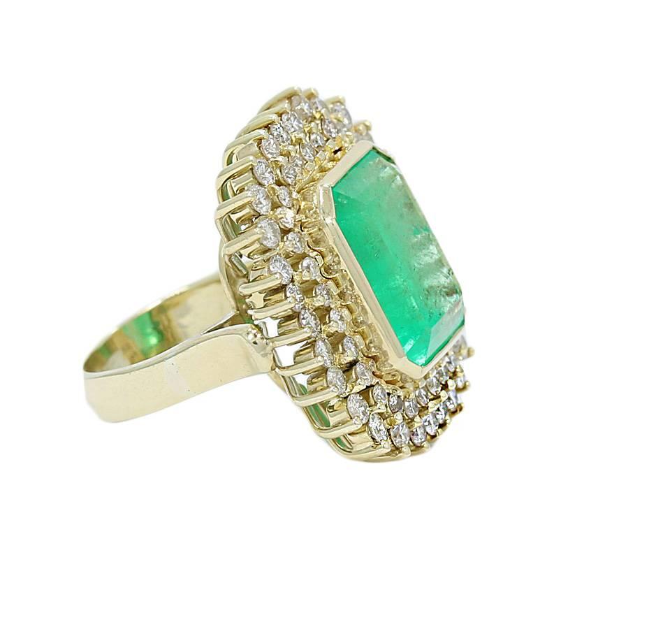 18k yellow gold emerald and diamond ring. The emerald weighs 12.00 carats total weight and the diamonds weigh 2.15 carats total weight. it measures 1.25 inches in height and weighs a total of 21.6 grams. The ring sits at a size 8.25 and can be