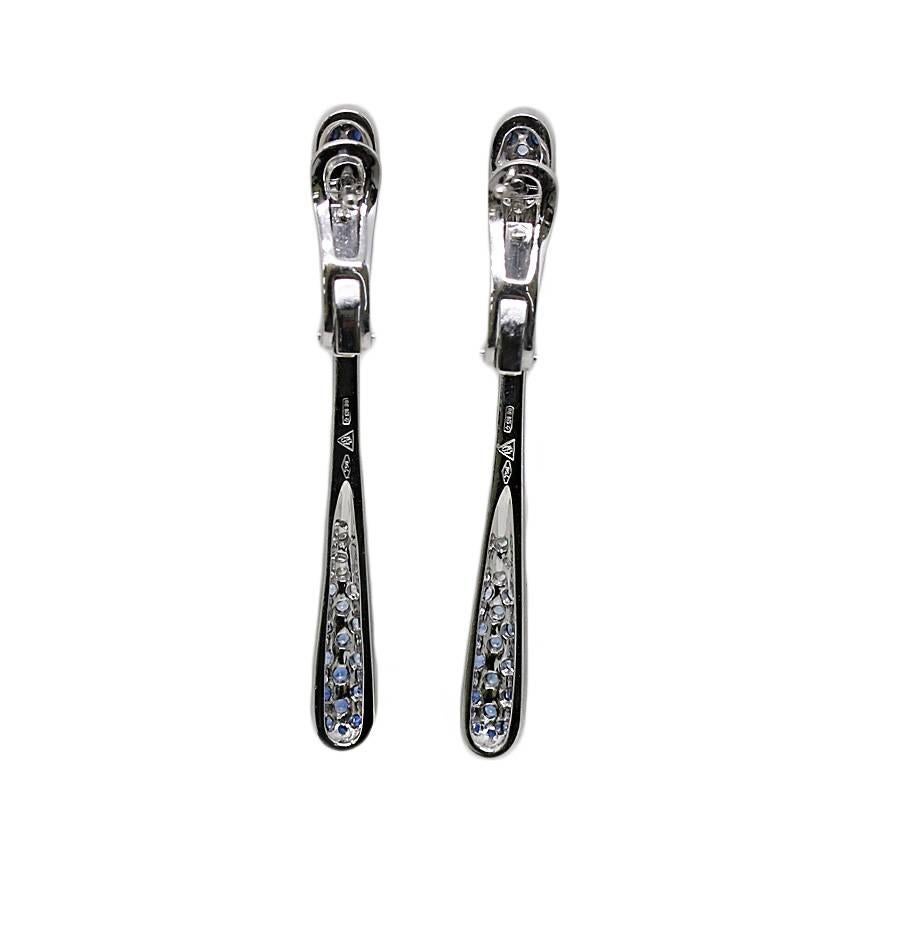 18k white gold diamond and sapphire dangle earrings. The earrings have 26 diamonds that weigh approximately .26 carats total weight and 44 sapphires that weigh approximately .65 carats total weight. They measure 0.875 inches in length and weigh a
