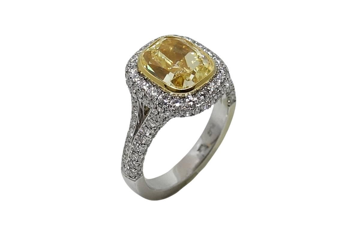 Platinum and 18K Yellow Gold Ring With A Center Fancy Yellow Cushion Cut Diamond Weighing A Total Carat Weight Of 4.00 Carats VS2 Color (GIA Report) This Ring Has A double Sided Micro Paved Halo and Split Shank Weighing A Total Carat Weight 1.48