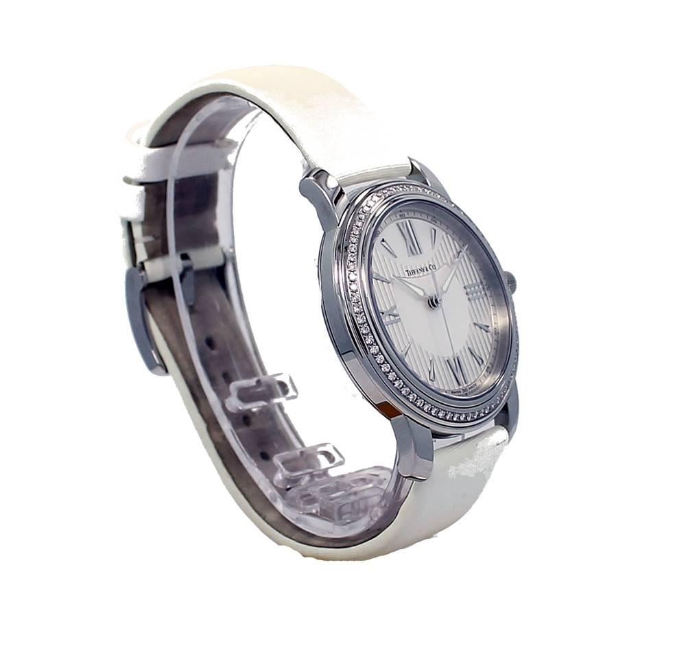 New ladies Tiffany & Co. Stainless Steel ladies Mark Watch with 72 Diamonds on the bezel, silver opaline dial, white mother of pearl accents and white leather strap. The watch has a 37mm case and a Swiss Quartz Movement. Comes with box, books and