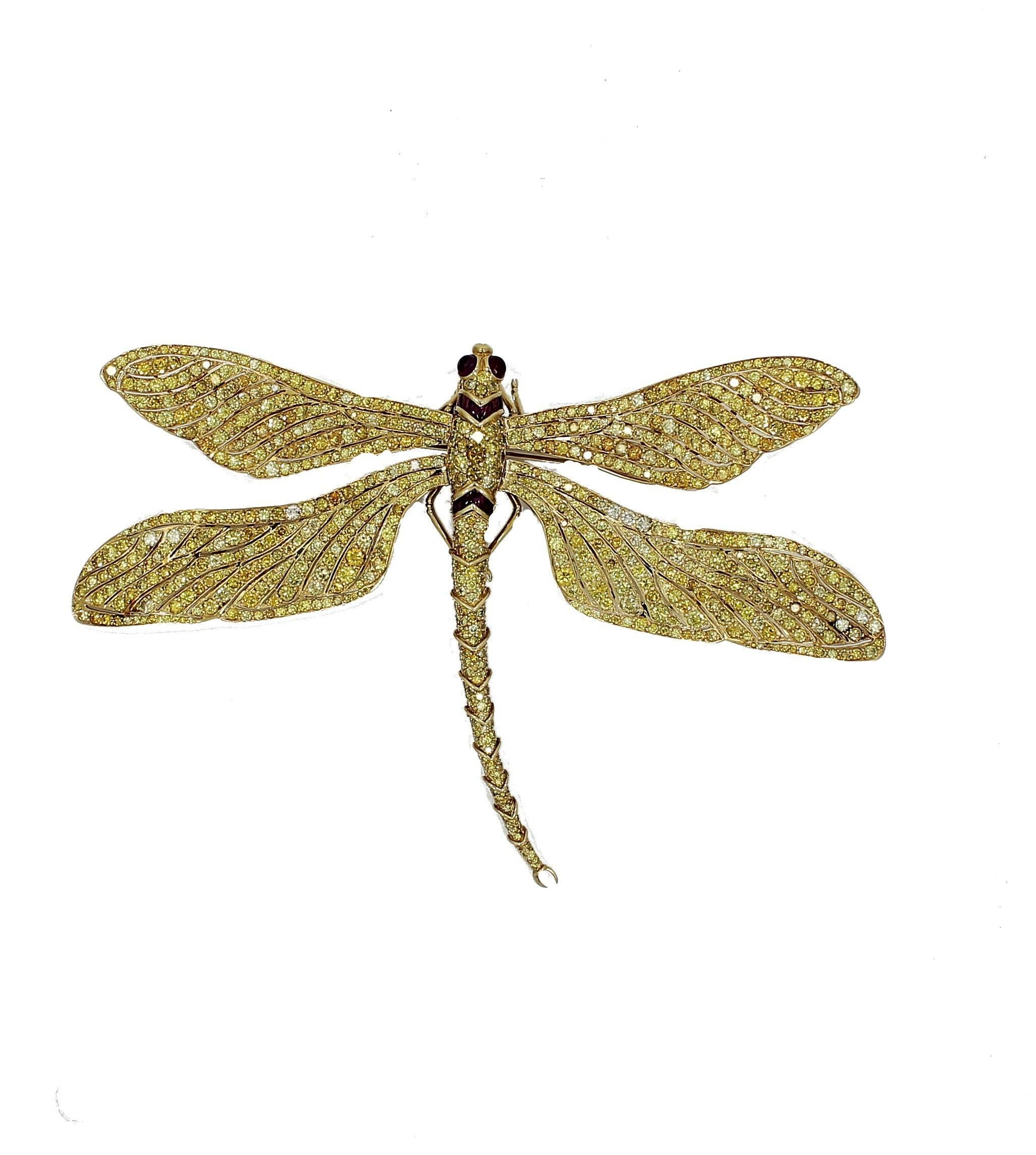 This Pave-set yellow diamond and yellow gold dragonfly brooch by Fred Leighton also features baguette-cut rubies at two cross points on the body and bulging ruby eyes. This Brooch has approximately 54.00 carats total weight in yellow diamonds. The
