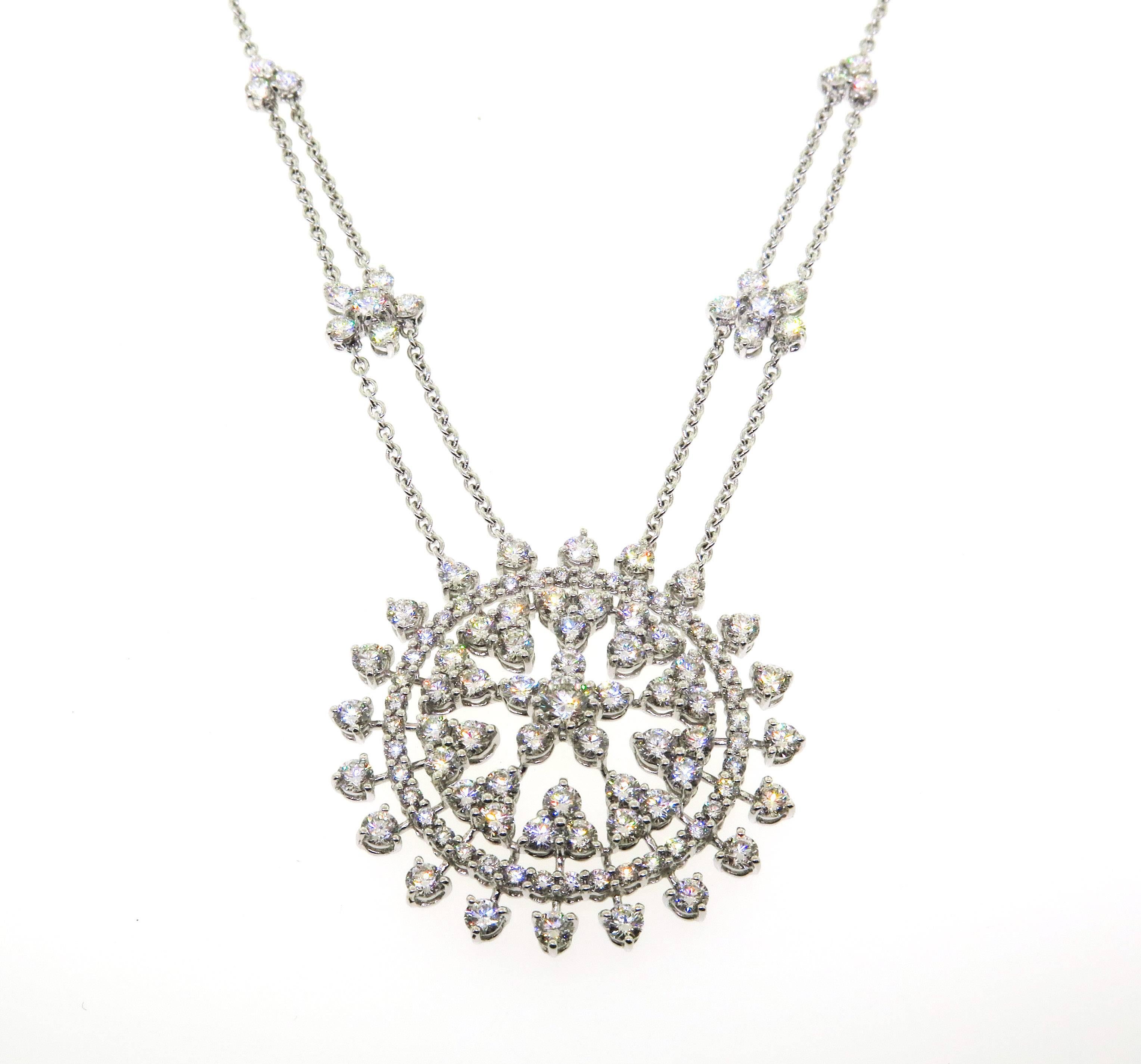 Elegant pendant containing 13.94 ctw of brilliant cut diamonds prong set in 18kt white gold. Features a stunning round center cluster of diamonds arranged in a open floral pattern . This pendant fully illustrates the exceptional workmanship of fine