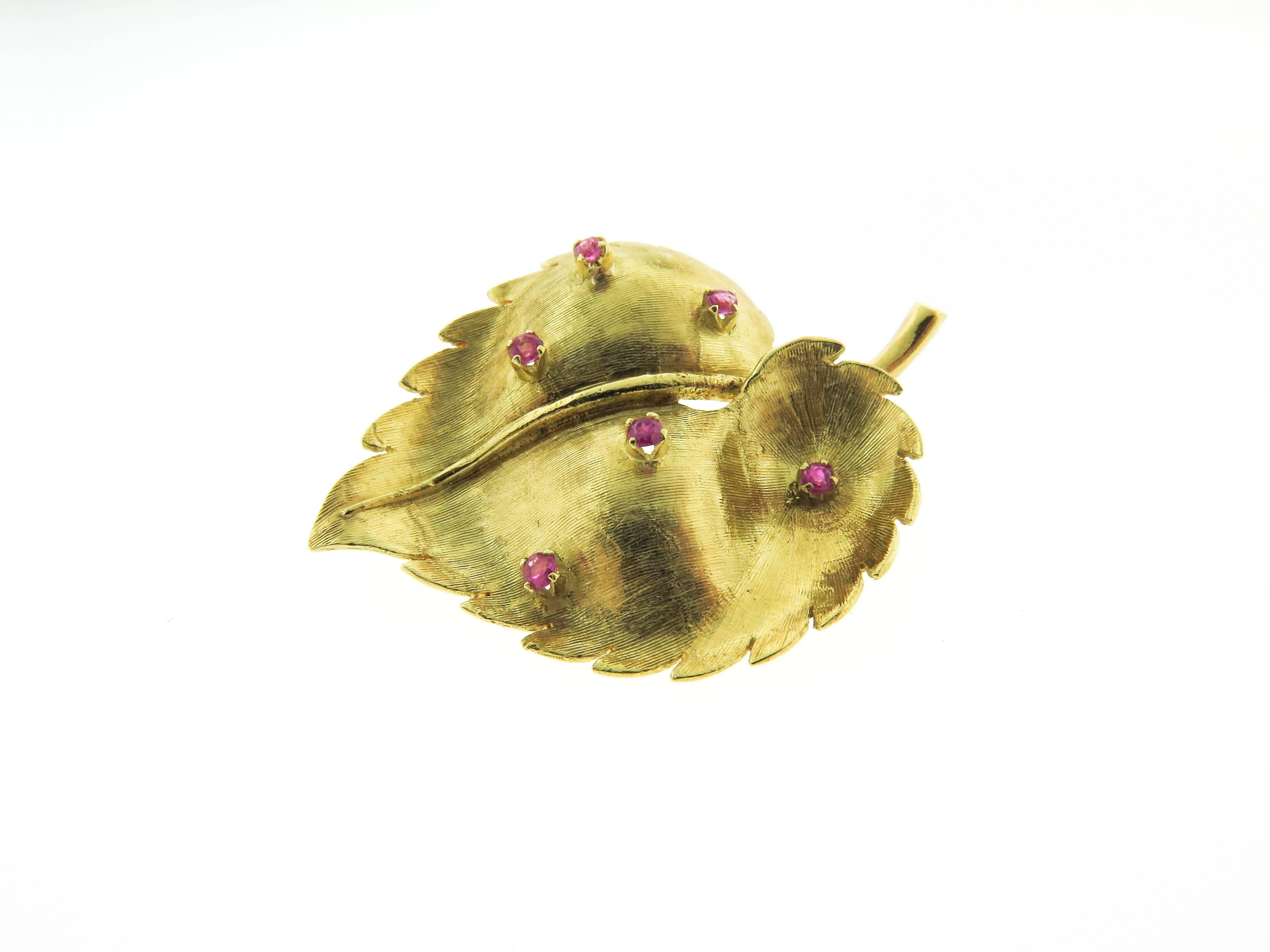 A vintage brooch in the form of a leaf, set with 6 round cut rubies and mounted in 18K gold, circa 1960. Measures approximately 39 x 29mm. Beautifully designed with satin finished details. 