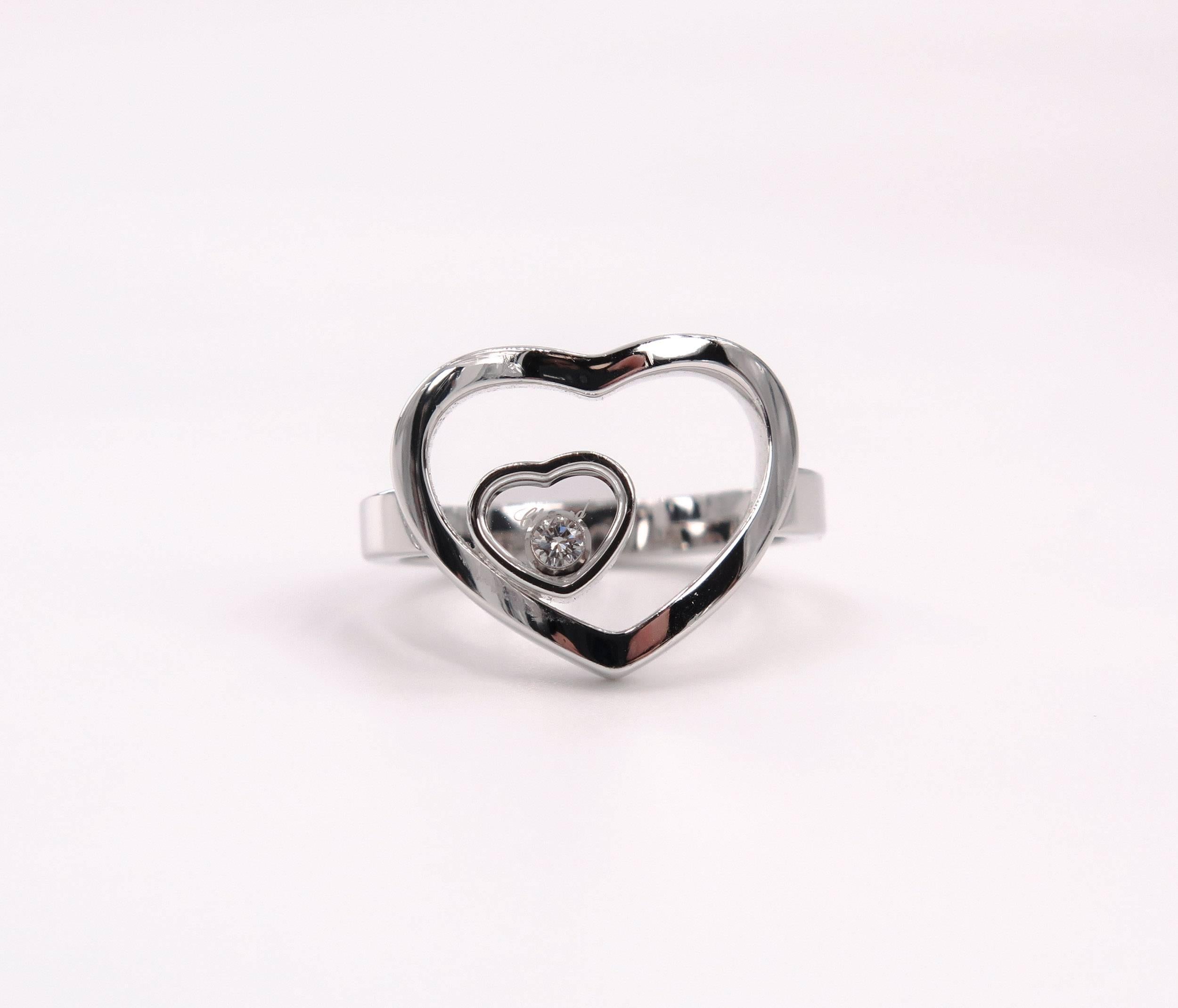 This Chopard ring in 18k white gold is part of the Happy Diamonds collection. Two hearts are delicately combined in a perfect marriage of sparkling harmony. The larger is designed openly to hold the smaller heart encasing a single Chopard moving