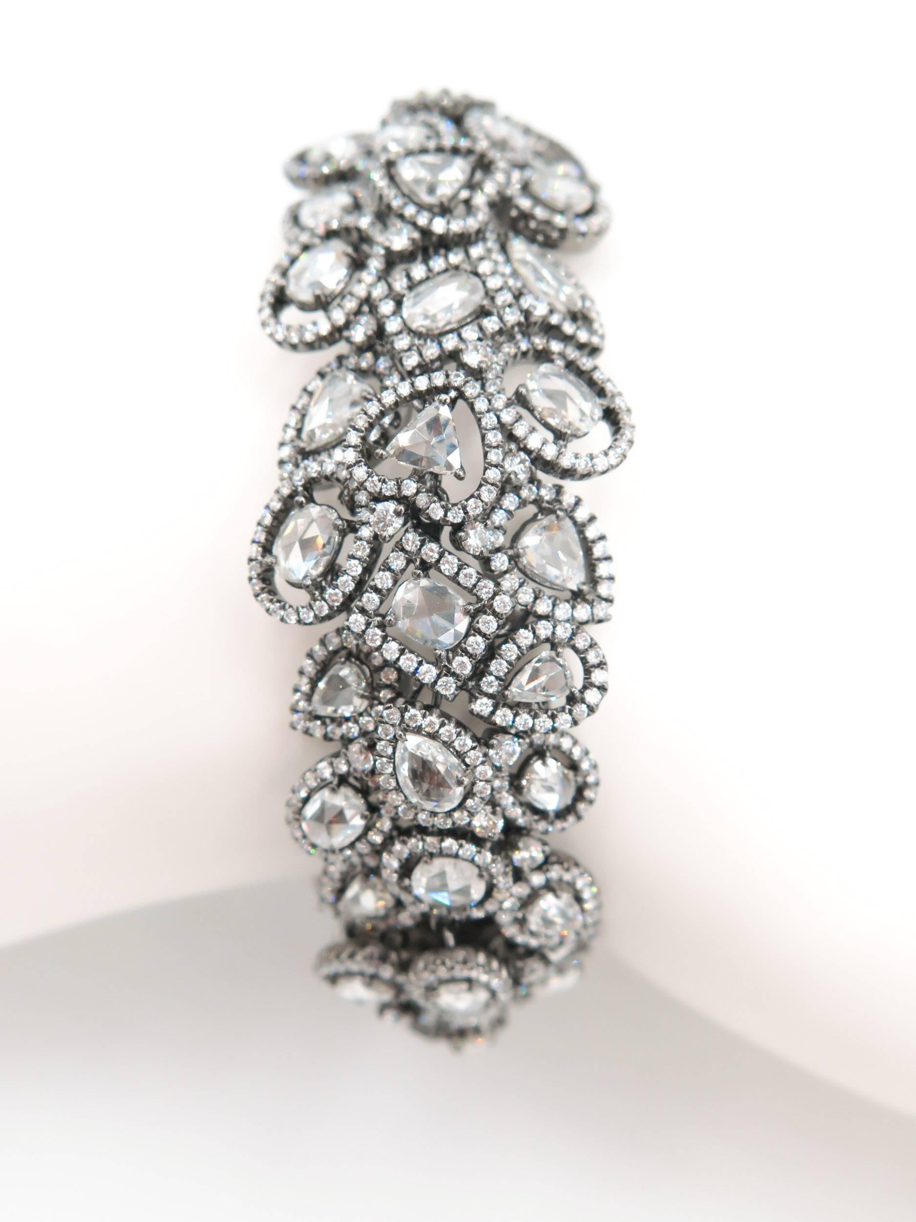 This magnificent bracelet sparkles with diamonds individually set with halos . Crafted in black rhodium-treated 18K white gold and boasts a remarkable design comprised of 21.22 carats of rose-cut white diamonds of different shapes and size.
