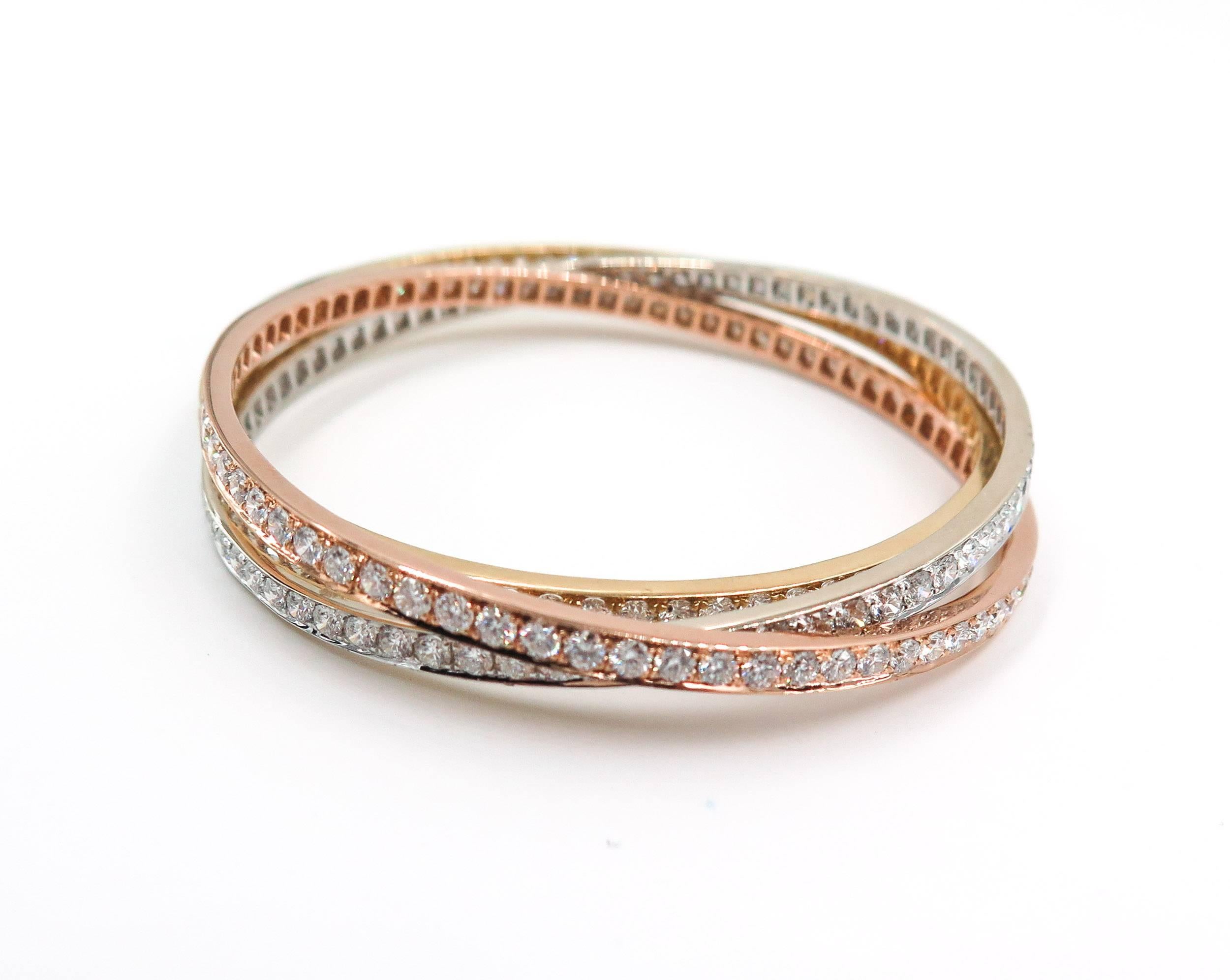 Rolling bangle bracelet, composed of three interlocking bangles in 18k yellow, rose and white gold. The gold bangle bracelets are set with 12.98 total carats of round-cut white diamonds. Slip on. Intended for small-sized wrists (63mm interior
