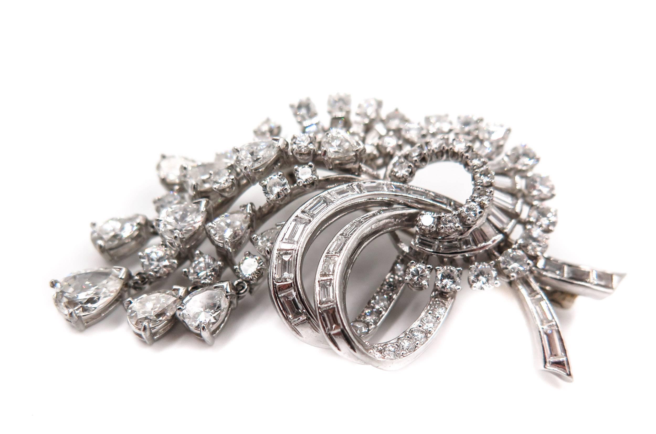 This beautifully designed estate piece of jewelry is a brooch which can be worn as a pendant masterfully designed in platinum, naturalistically inspired and diamond swathed scrolls and crescent-shaped profiles. 
Exuding elegance and astonishing