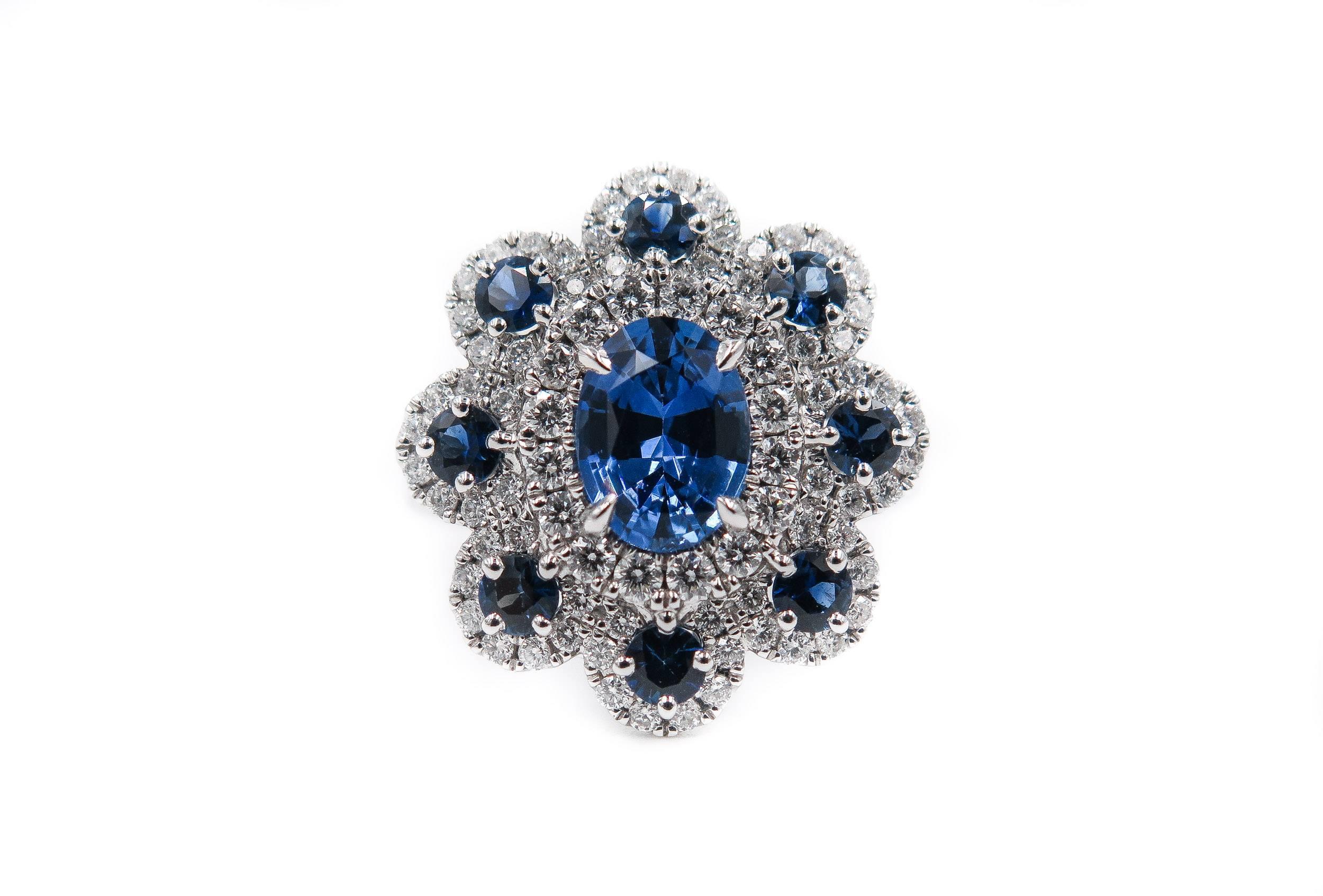 A gorgeous sapphire and diamond ring handcrafted in 18K white gold.
The central oval shaped sapphire, weighing 1.40 carats, in a four claw setting, surrounded by round cut sapphires weighing 0.76 carats, each set in a halo of brilliant cut diamonds,