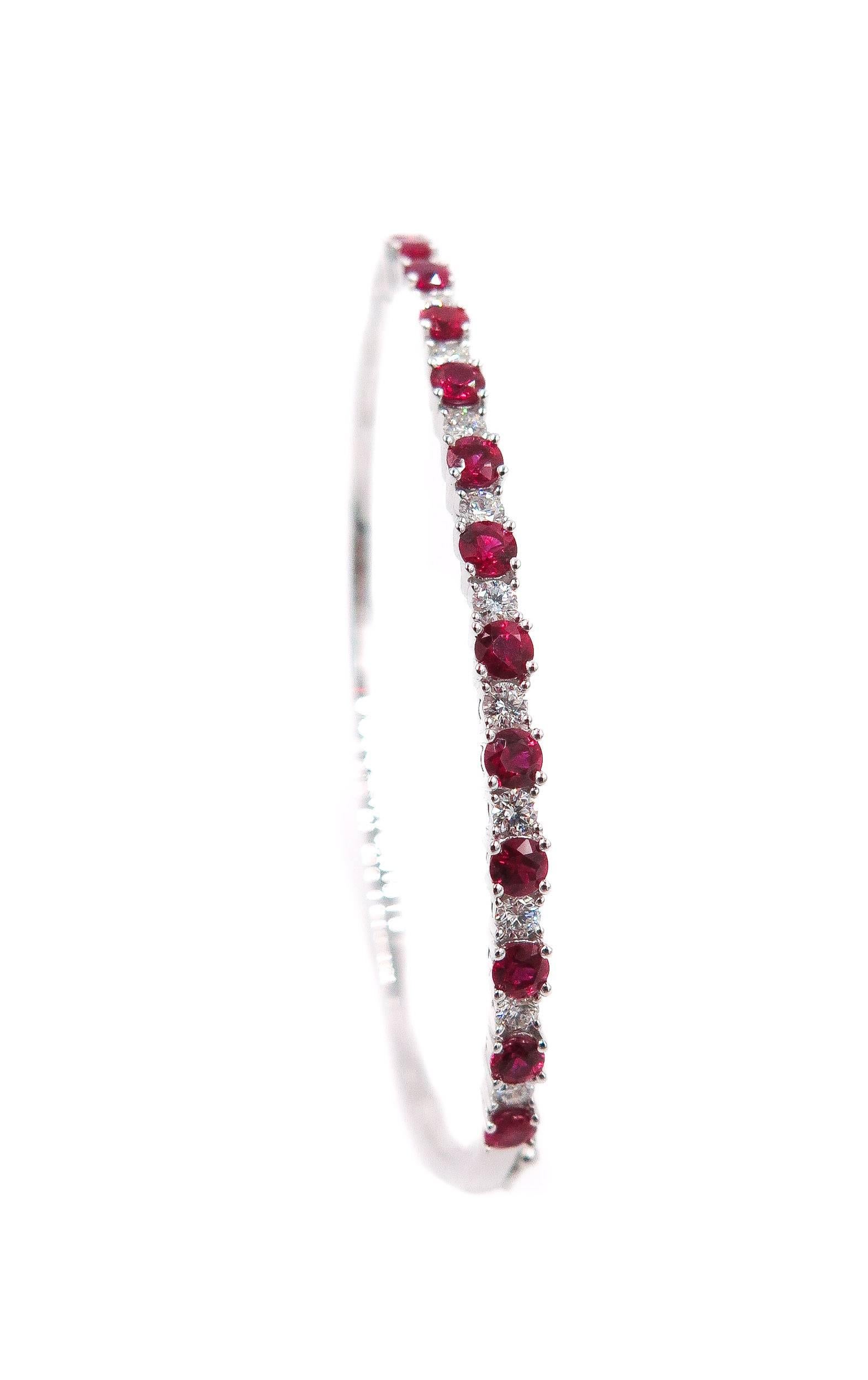 Handcrafted to perfection, this halfway ruby and diamond bangle should be halfway to your shopping cart! 
Alternating rubies with slightly smaller diamonds, this varied design is a work of art. 
Perfectly matched 14 round cut rubies, with a carat