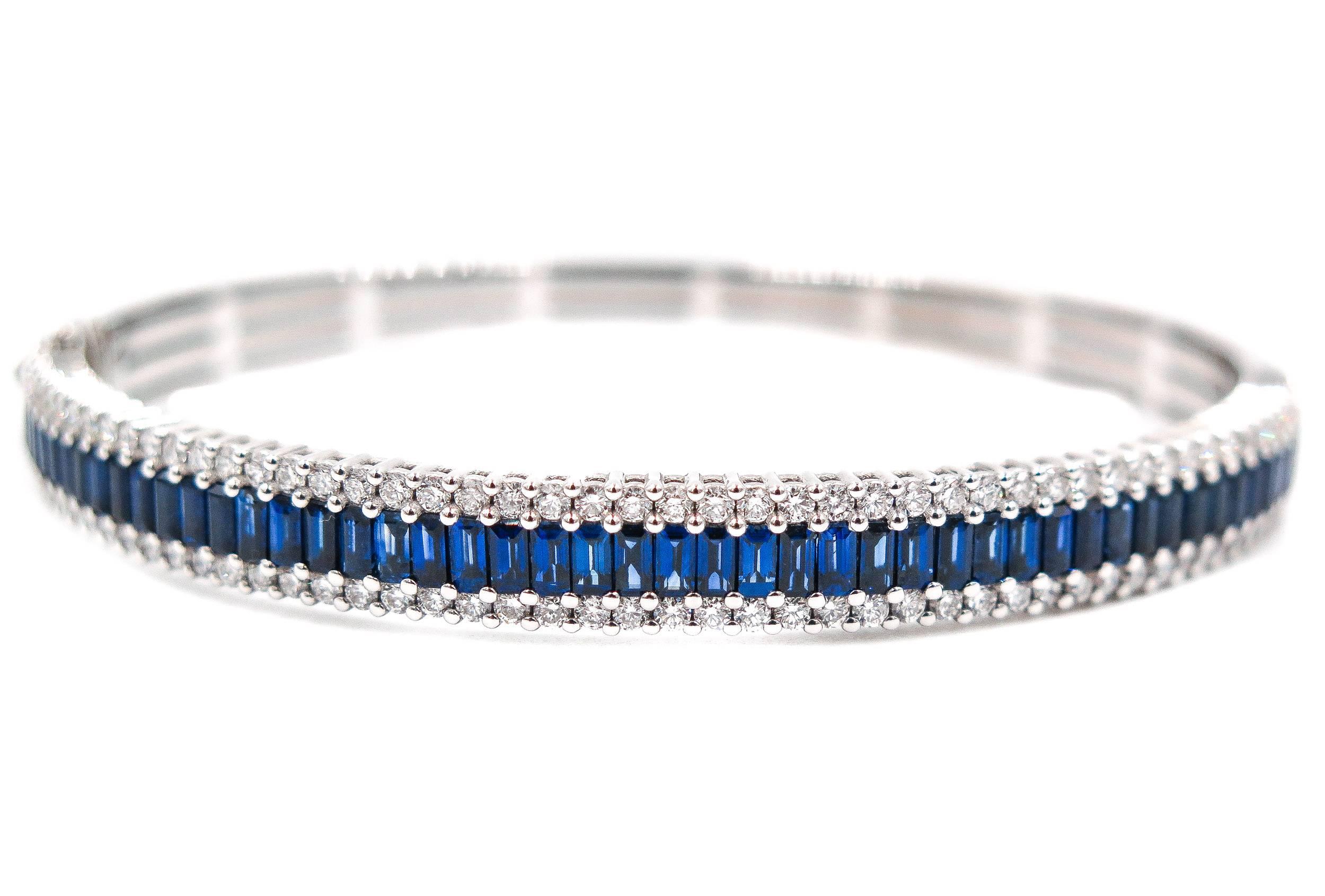 Absolutely gorgeous baguette cut blue sapphires set between two rows of white round diamonds. 
This bracelet is designed to showcase the beauty and brilliance of the stones. 
The 6.5 mm wide bangle bracelet is handcrafted in 18K white gold, and on