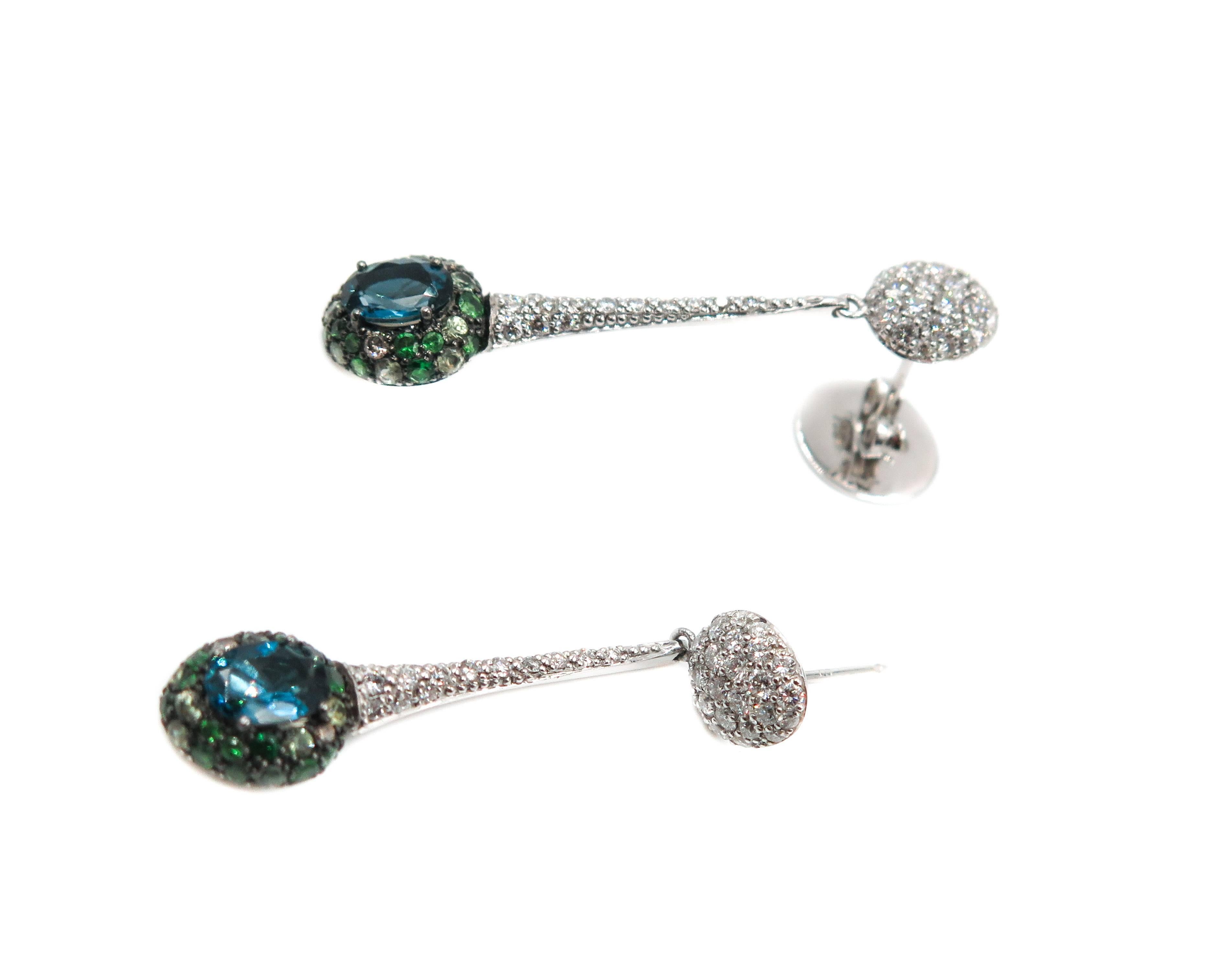 Sleek, elegant and stylish... are just few of the adjetive's that can be used to describe these earrings.
Handcrafted in Brazil by Brumani, in 18k white gold. This pair of long drop earrings, feature an oval blue tourmaline with accents of green