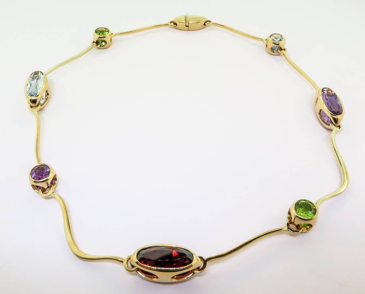 This fine necklace features garnet, amethyst and peridot finely handcrafted in 18k yellow gold by the Italian jewelry designer Manfredi.
