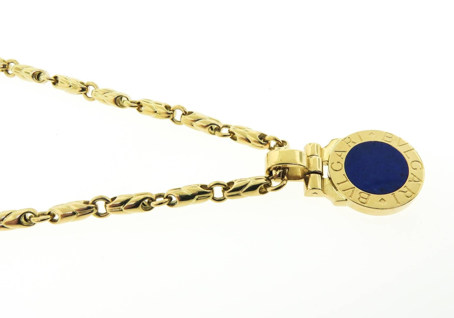 This Bvlgari piece is finely crafted from solid 18k yellow gold. It features a beautiful circular lapis pendant inscribed with Bvlgari - Bvlgari, attached to a sturdy chain. The chain is 22