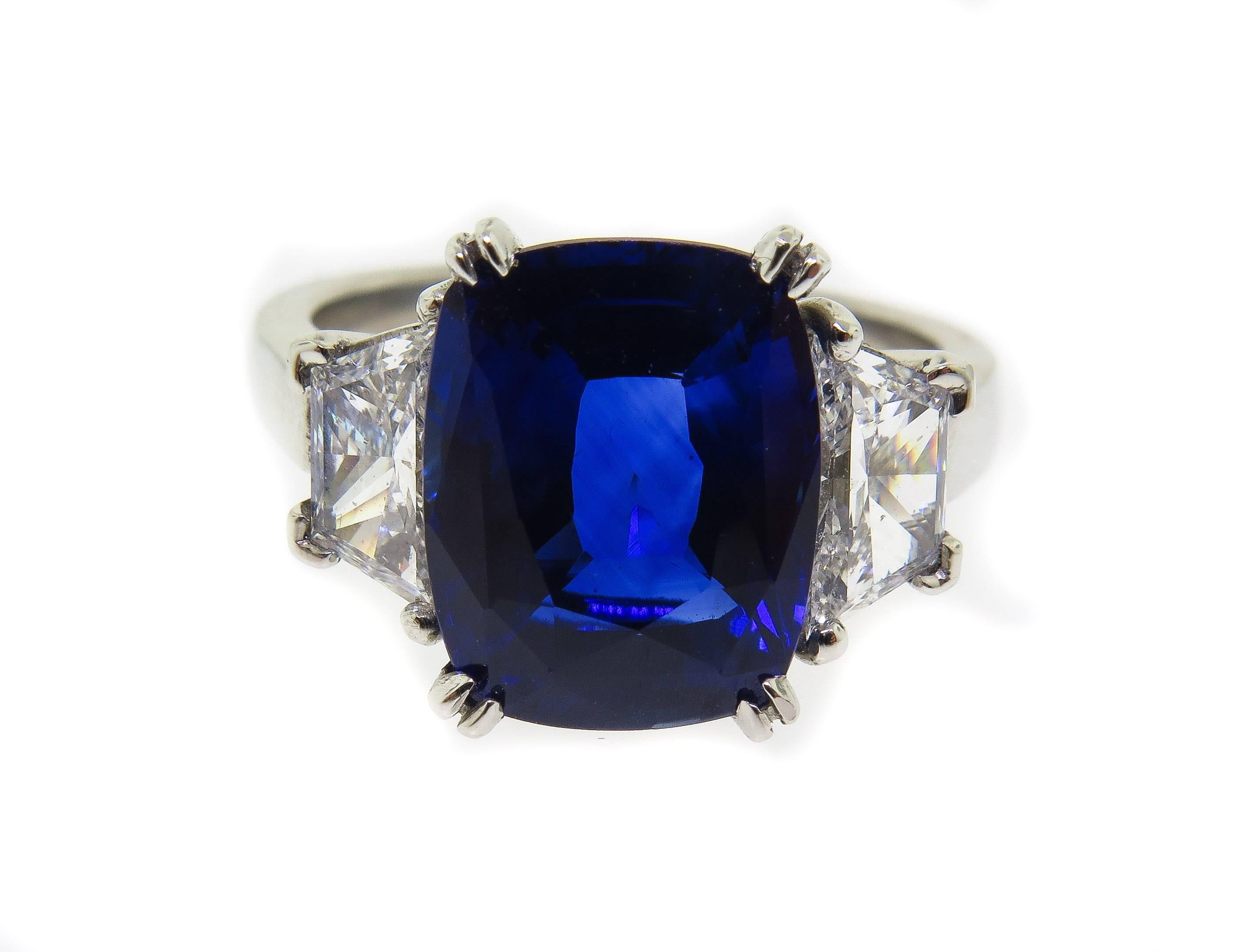 Stunning Sapphire and Diamond Ring with a beautiful cushion cut blue sapphire. The sapphire weighs 4.98 carats. The trapezoid diamonds on either side weigh 0.51 carats each totaling 1.02 carats and have G color and VS clarity. The ring is set in