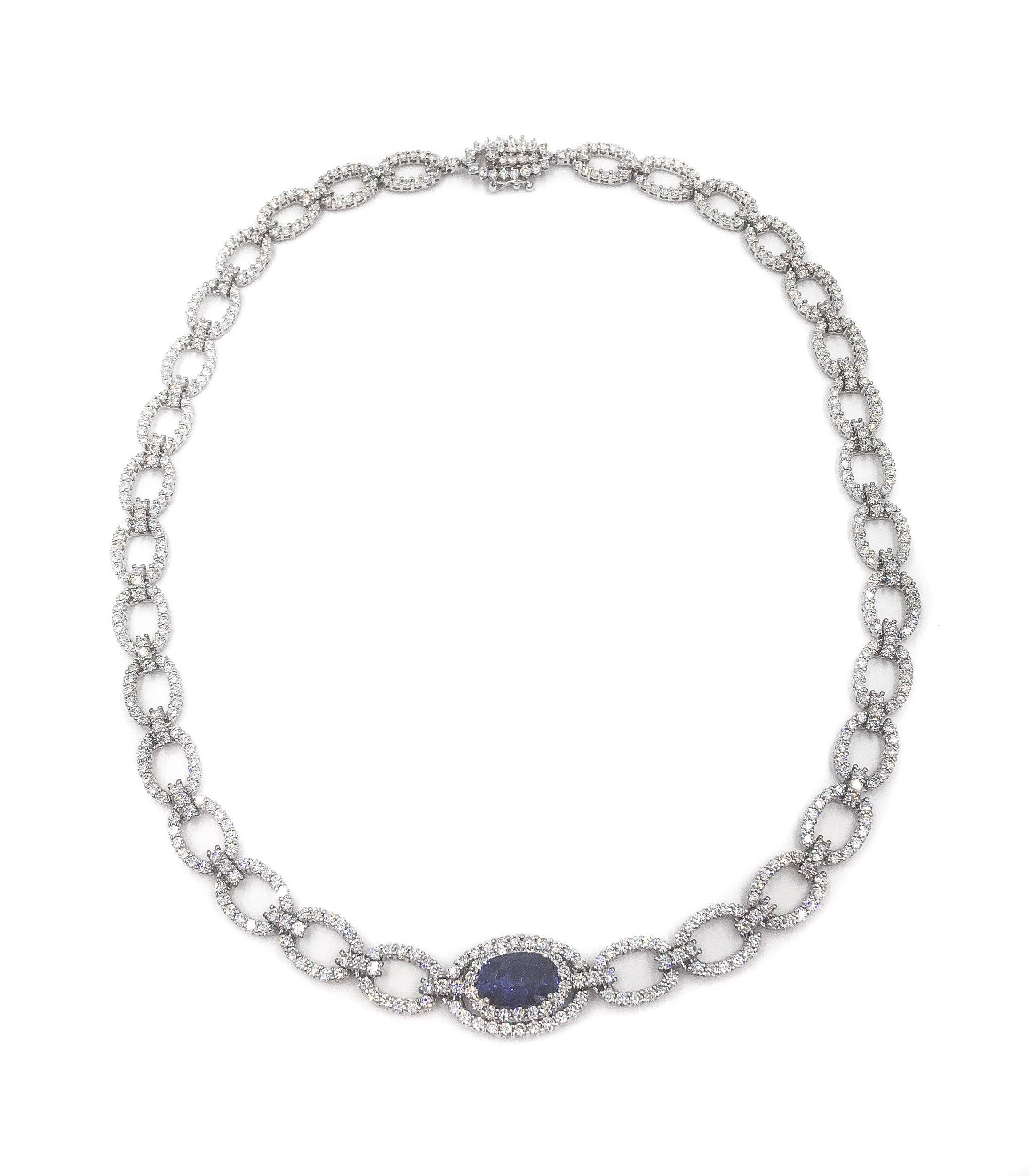 The enchanting oval sapphire is horizontally positioned in the center of this diamond necklace composed of a semi-rigid design of open oval links of round brilliant cut diamonds, together weighing approximately 10.72 carats, graded G-H color and