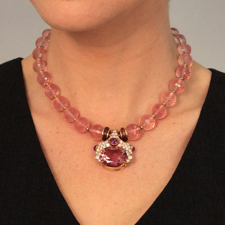 A stunning confection in pink, this 18k yellow gold necklace features an array of superb colored stones and diamonds. The center element is set with a 22ct pink tourmaline of exceptional quality, three fine pink sapphire cabochons totaling 3.25