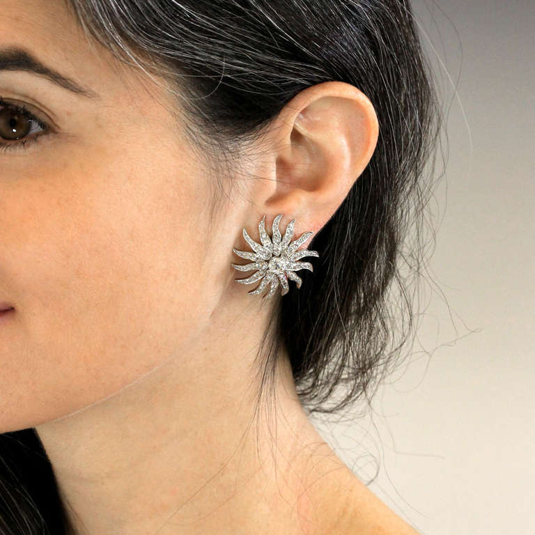 Circa 1920s, platinum over 14k. These fabulous earrings excite the senses with bright white diamonds set in a distinctive deco sunburst theme. Each has a .75 carat center stone (G-H color, SI1 clarity) and 3.50 carats overall of additional diamonds.