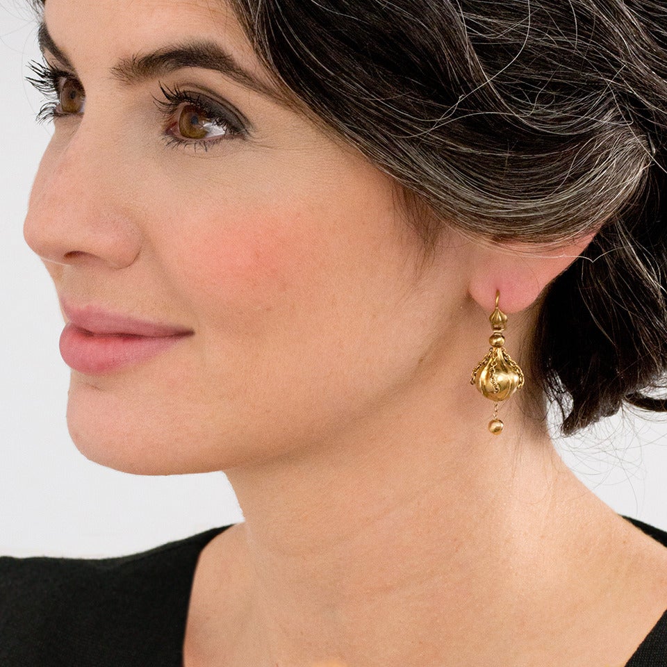Circa 1890s, 15k, England.  Beautifully crafted with fine details in warm 15k gold and festooned with tiny chains and a dangling ball, these antique English earrings possess the enchanting charm of a bygone era. These earrings are finely crafted and