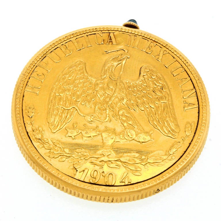 Cartier Yellow Gold Mexican Coin Watch, circa 1950s. Famous for fascinating timepieces, this watch is cased inside a gold coin. Given as a gift to an ambassador to Mexico, this version features a Mexican 20 pesos piece. The sapphire-set crown winds,
