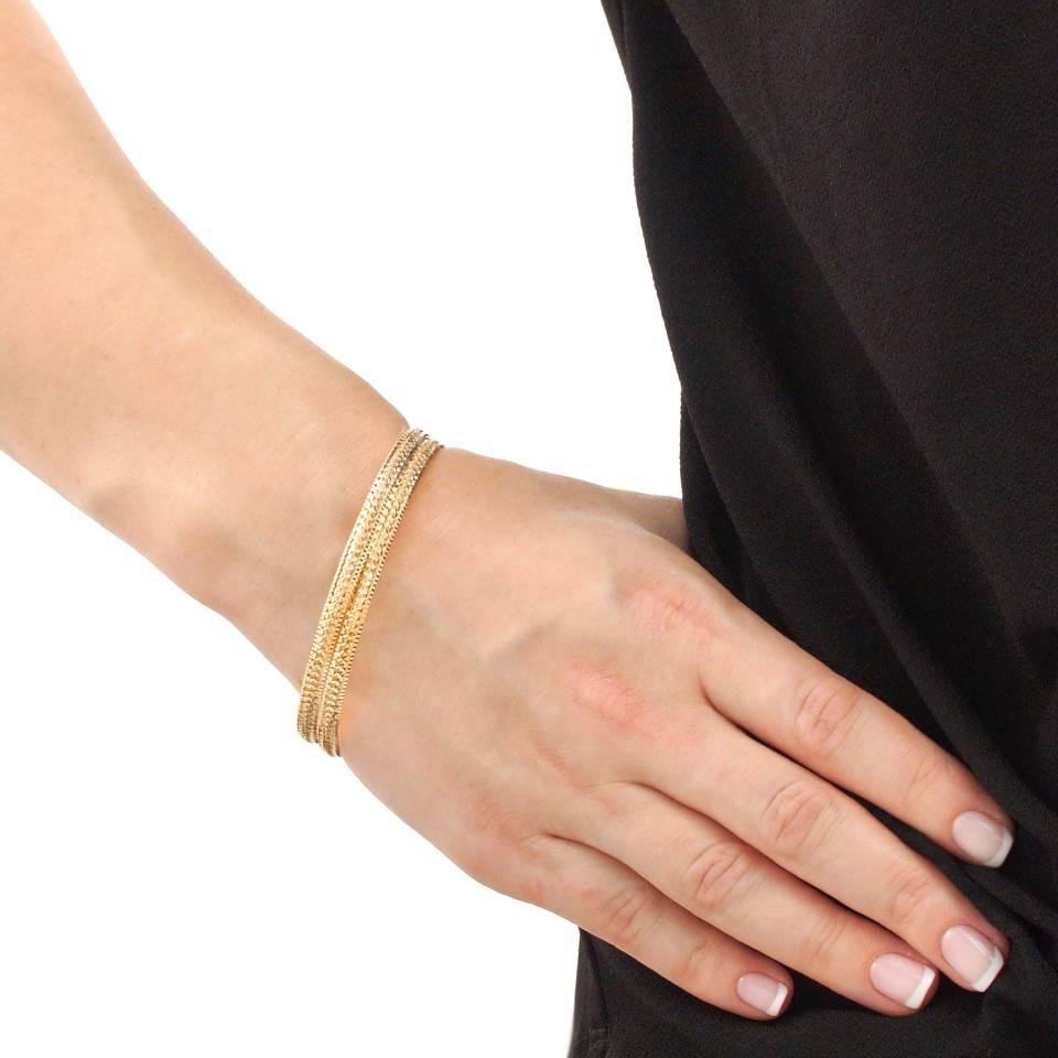 Circa 1970s 21k.  This pair of 21-karat gold bangles have an intricate bright cut motif that sparkles from every angle.  Perfect worn on their own, or mixed into a stack of other bangles, they are handmade in solid yellow gold. 
 
Shown in one