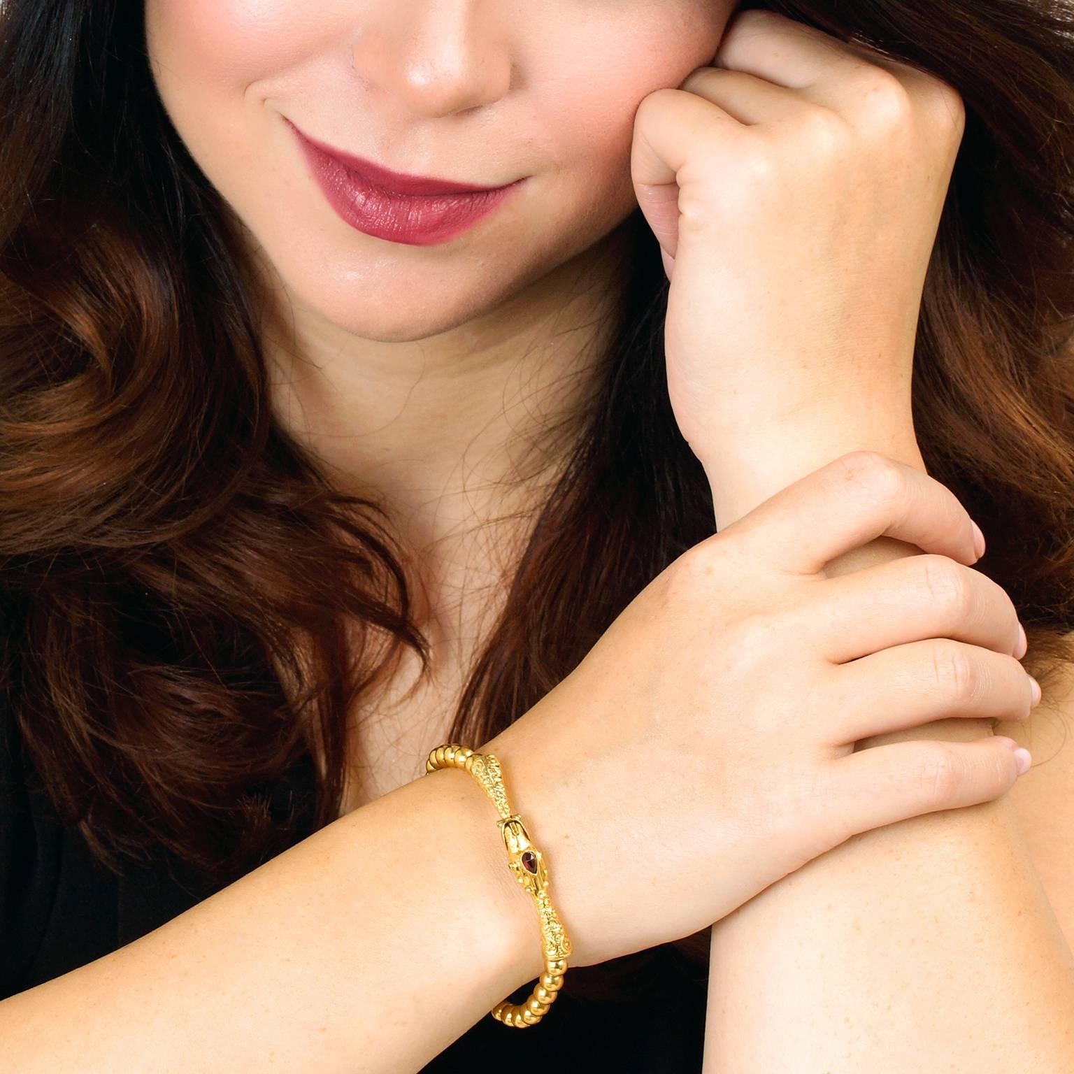 Circa 1880s, 14k.  This marvelous nineteenth-century bracelet pairs gold beads with a fourteen-karat, garnet-set catch, depicting a snake. This charming motif draws on ancient art and symbolism for a look that is unique. Well-made and delightfully