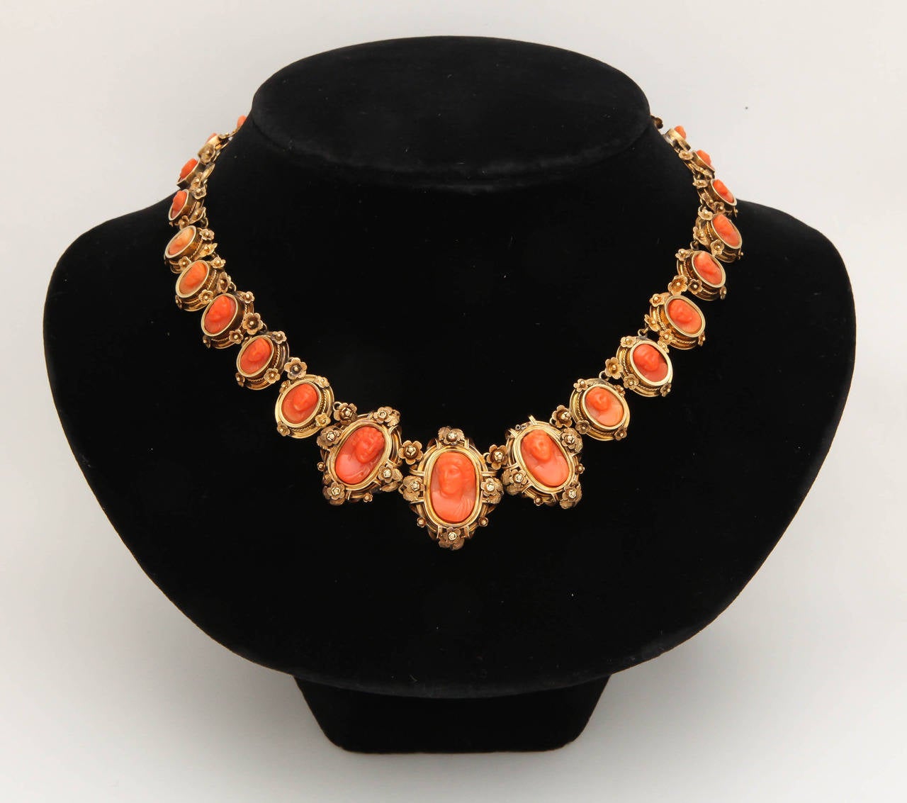 A beautiful carved coral necklace designed as a graduated line of twenty-nine oval coral cameos carved in high relief, most likely by the master engravers of Torre del Greco in Naples. each framed in gold enhanced at intervals with raised gold