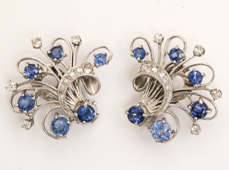 Designed as openwork platinum ribbon tied floral sprays, each is set with six oval and circular-cut sapphires and enhanced with nine small diamonds. The total weight of sapphires is approx 4.70 cts. Mounted as clips. 

1 1/8 x 1 in. (w x l) (2.9 x