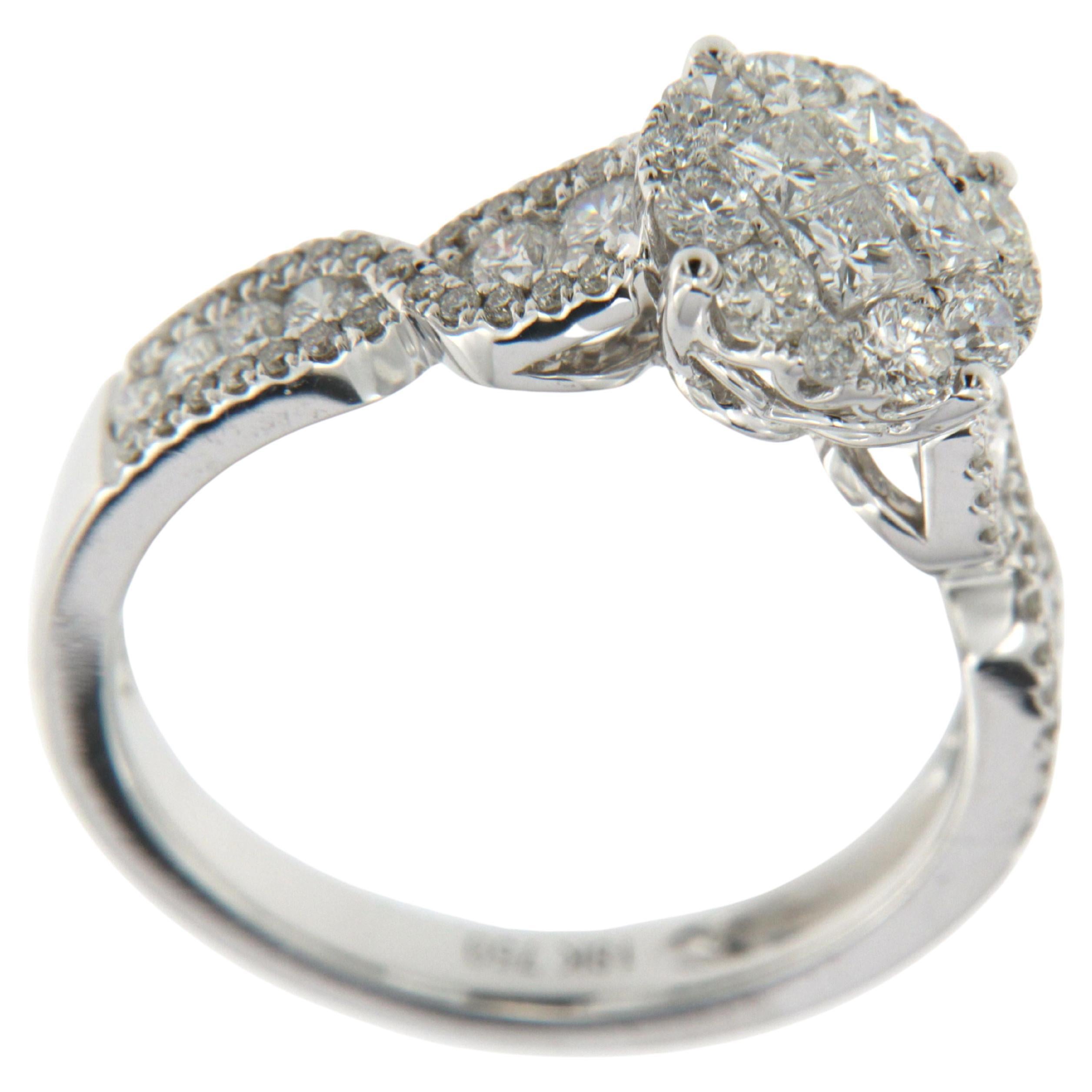 Exemplifying the pinnacle of meticulous artistry and luxury, this ring in 18 karat white gold beautifully showcases a contemporary approach to traditional elegance. At its center, an illusion cluster of 4 Princess Cut Diamonds with a combined weight