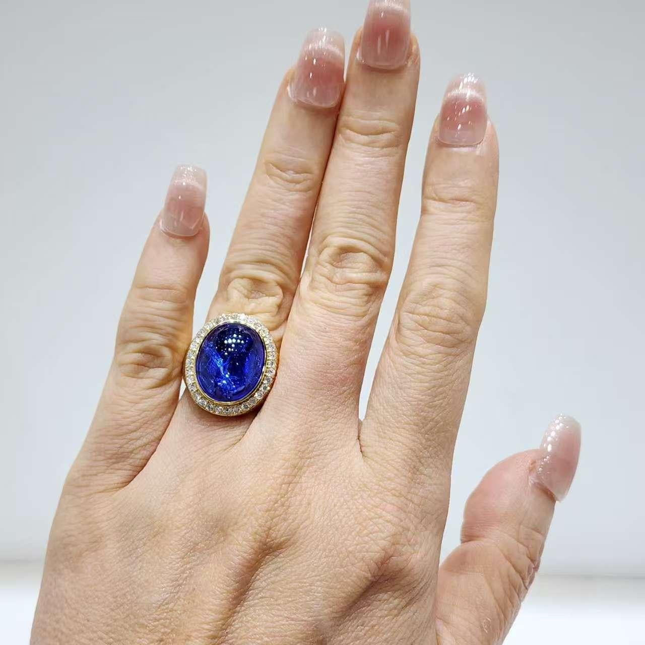 Cette bague de cocktail remarquable met en valeur une tanzanite ovale cabochon de 11,26 carats, qui brille par ses riches teintes bleu-violet et sa texture intérieure captivante. Sertie dans de l'or jaune 18 carats, la pièce maîtresse est entourée