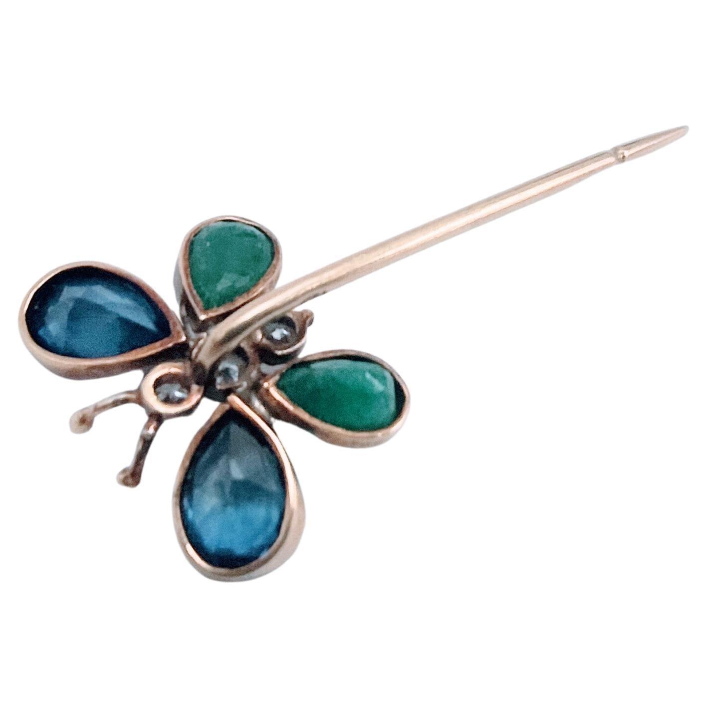 Delicate butterfly Stickpin with bise set made in yellow gold 18 Karats 1.41 grs  weight, The wings composed of a pair of blue sapphires in the form of a pear of 1.34 carats even and two Emeralds in the form of pear of 0.60 carats the pair. The