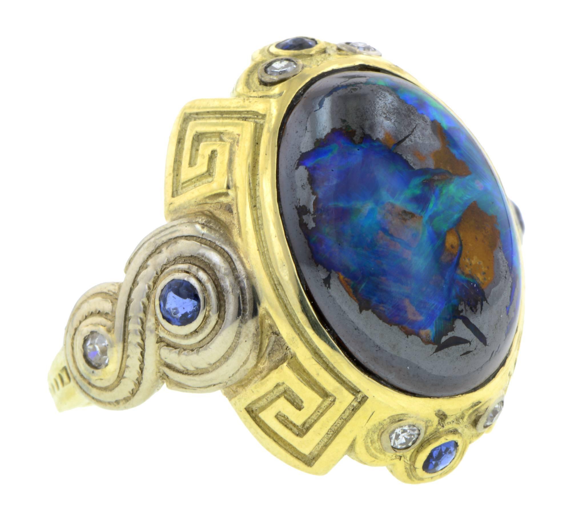 Art Deco Boulder Opal, Sapphire & Diamond Ring centering an oval boulder opal measuring app. 15.2 x 11.4mm, framed and flanked by four sapphires measuring app. 1.5 - 2.0mm and six diamonds (5 Single cut, 1 Round Brilliant cut) weighing app.