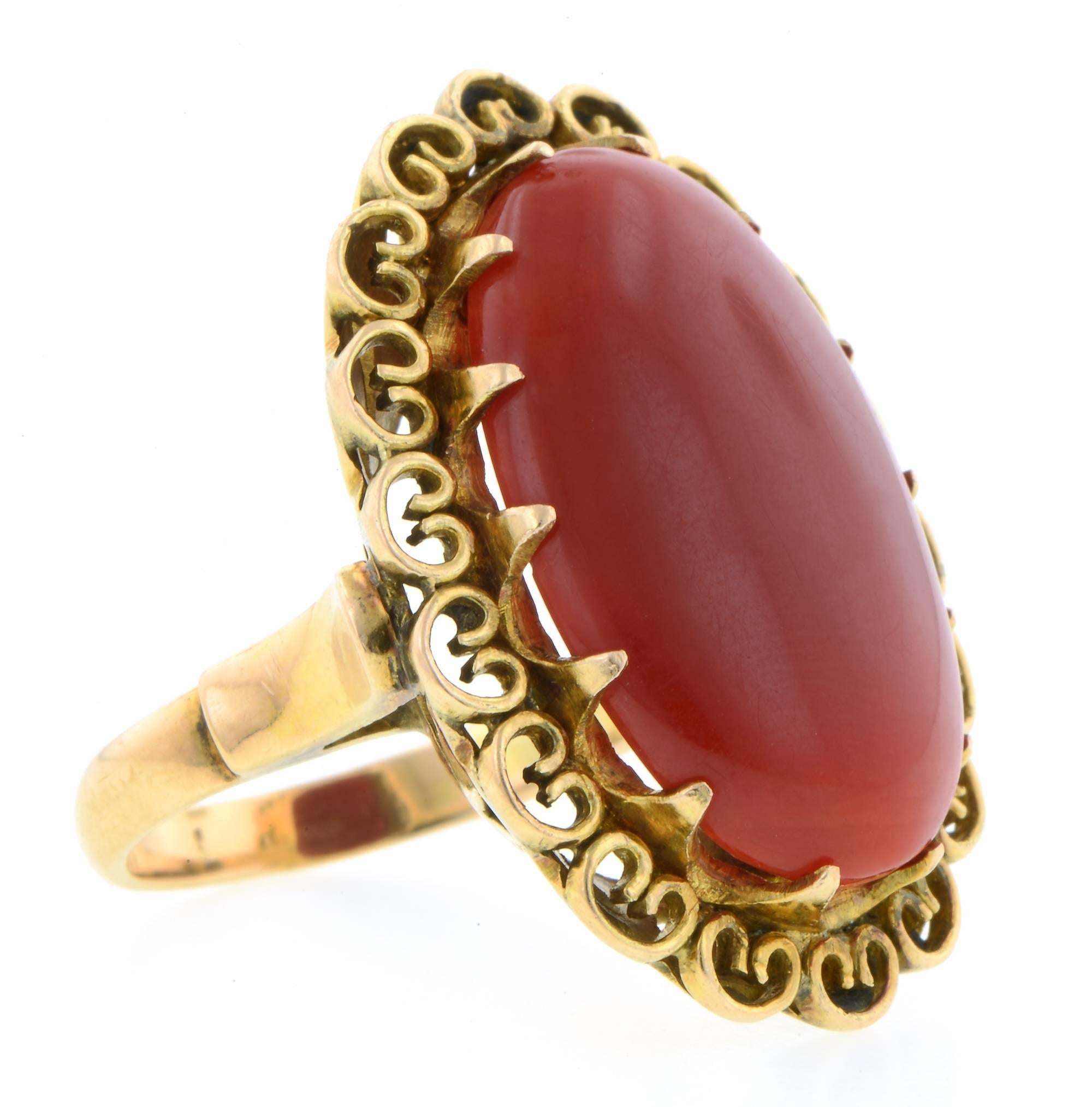 Vintage oval coral cabochon ring centering an oxblood red coral measuring app. 21 x 14.3mm., in a scroll work frame, fashioned in 14k.  Size 5.