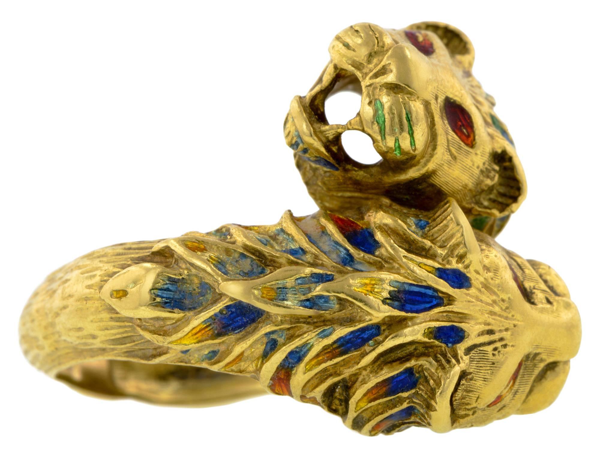 Two engraved lion heads with green, blue, red & yellow enamel* in a crossover design, fashioned in 18k. Second half 20th century. Size 7.5 This ring cannot be sized. *Although vitreous enamel forms a hard, durable surface, it is susceptible to