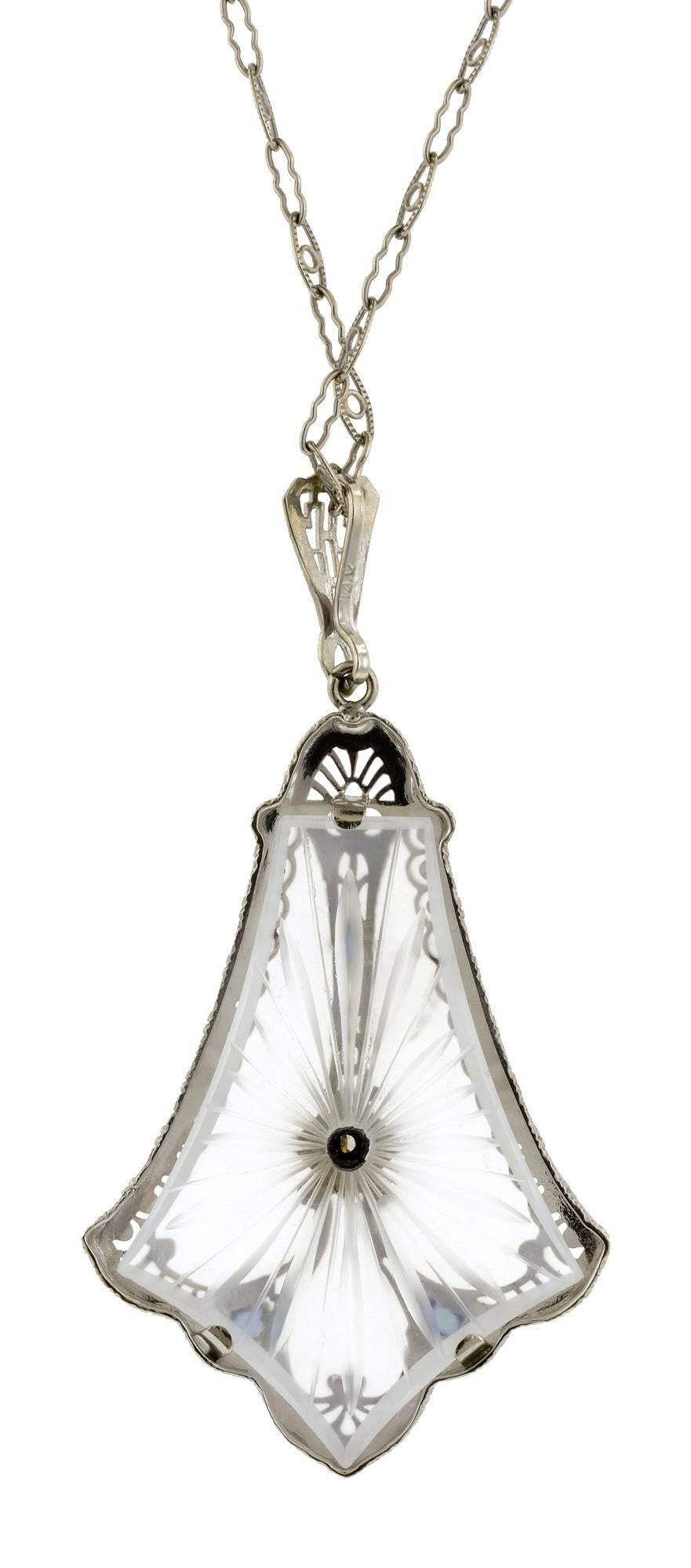 Art Deco rock crystal diamond pendant centering a Round Brilliant cut diamond weighing app. 0.03ct, set with three emerald* accents, in a filigree mounting, fashioned in 14k white gold.  Suspended from a filigree chain measuring app. 16