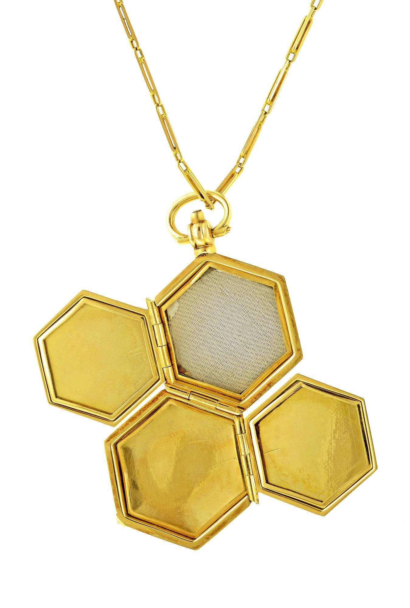 Hexagonal multipage locket necklace features a spring opening mechanism revealing four framed compartments for photos. Locket measures 7/8 inch in width. Fashioned in 15k yellow gold. Suspended from a 17.5 inch long, 15K yellow gold, fancy link bar