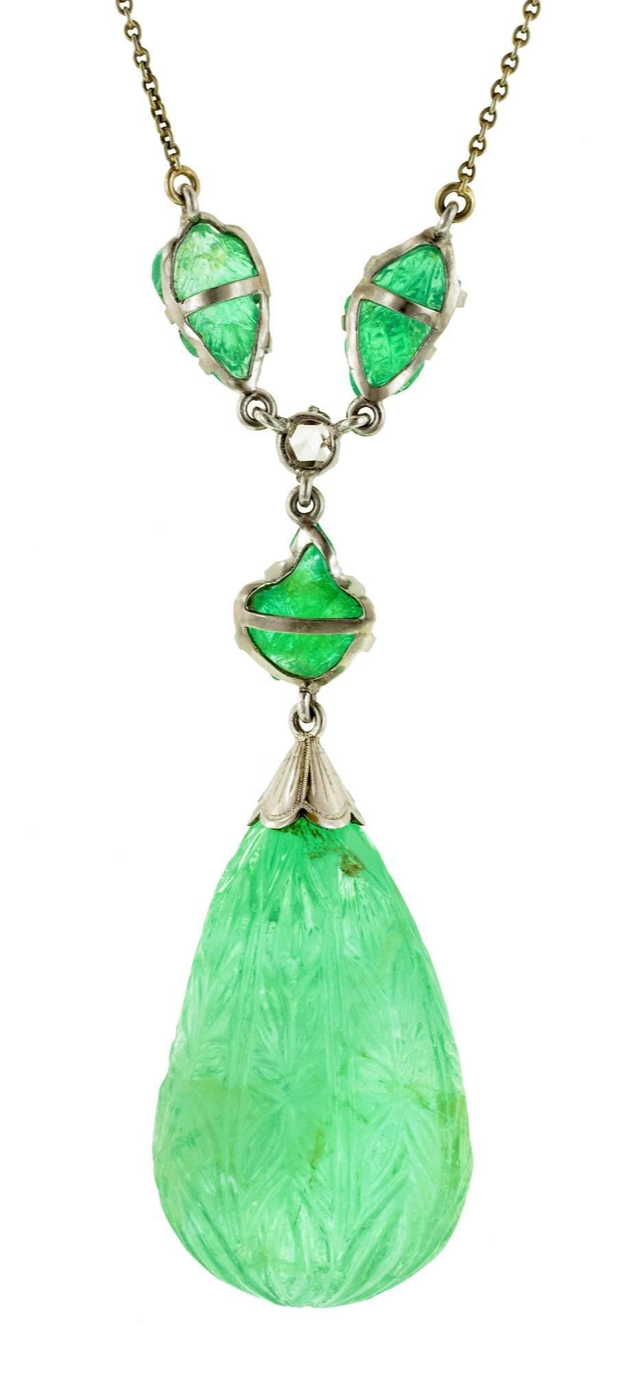 Art Deco carved emerald & diamond lavaliere necklace measuring 18 inches in overall length; featuring a carved emerald drop pendant measuring approx. 29 x 19.5mm (at widest), weighing approx. 32.50ct; with a foliate motif. Suspended by three carved