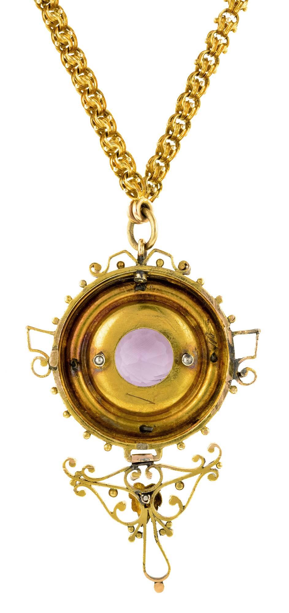 Victorian amethyst necklace centering a round amethyst measuring approx. 15.65mm, within a foliate motif frame in two tone gold.  The drop measuring approx. 2 3/16 x 1 7/16 inches (including bail), suspended from a fancy link chain measuring 20 1/4