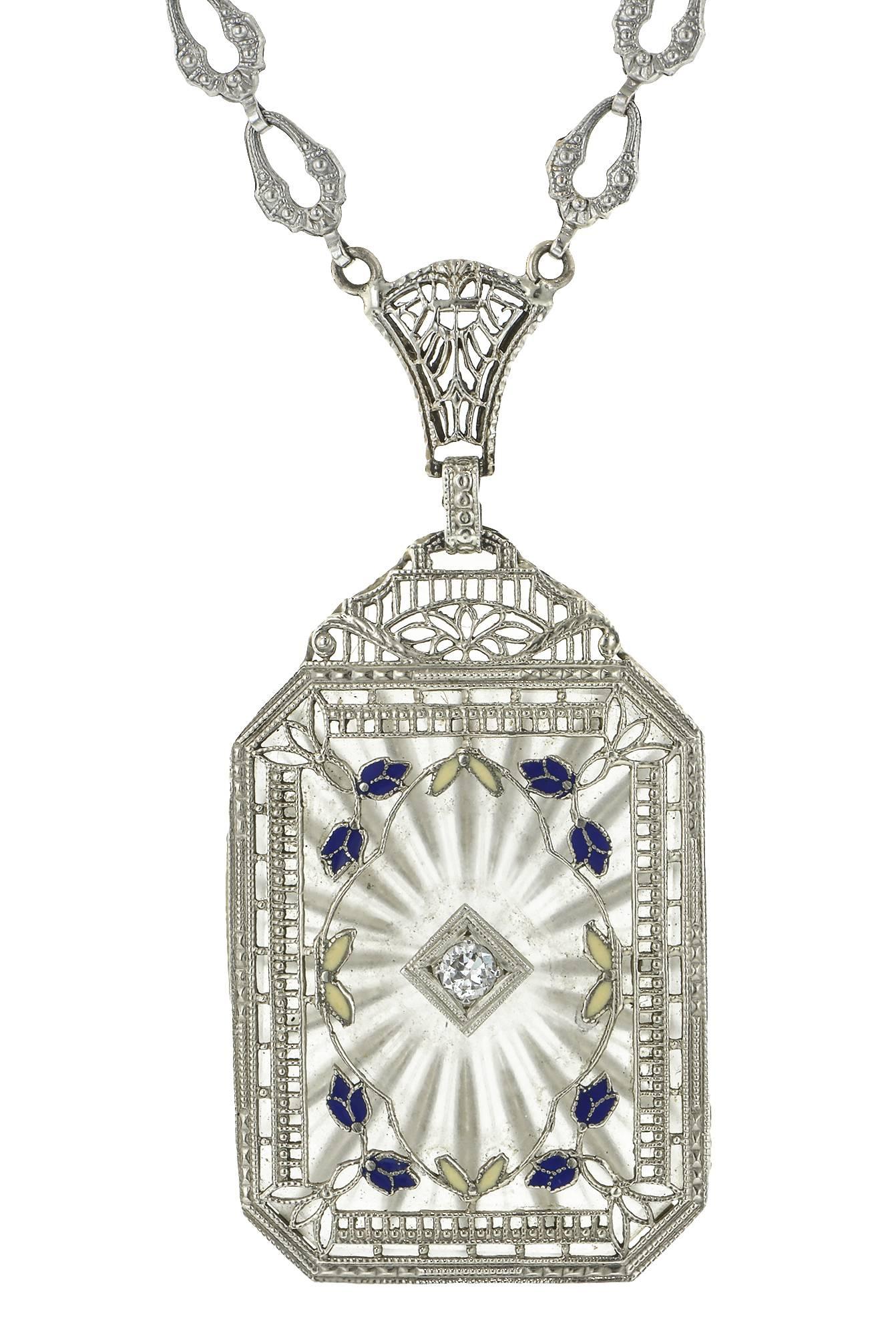Art Deco carved rock crystal, diamond, enamel filigree necklace featuring a rectangular carved rock crystal plaque measuring 1 1/8 x 7/8 inches; reverse carved in a sunburst pattern and pierced in the center with a bead set Transitional Round