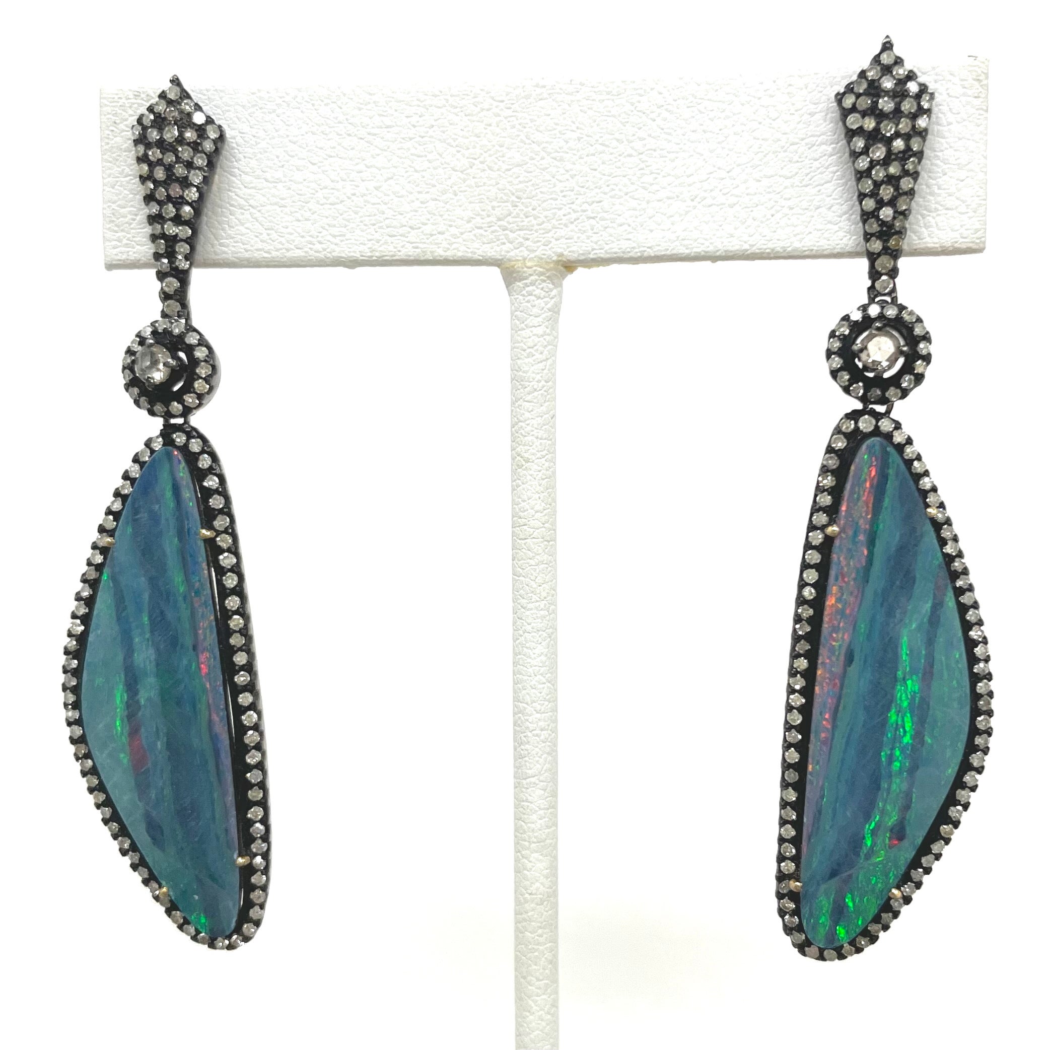 Description
Eye catching, exquisite, vivid blue color opal with a touch of fire. This pair was cut from one stone creating a mirror image of each other. The opals are embellished with white pave diamonds and a center champagne diamond, all of which