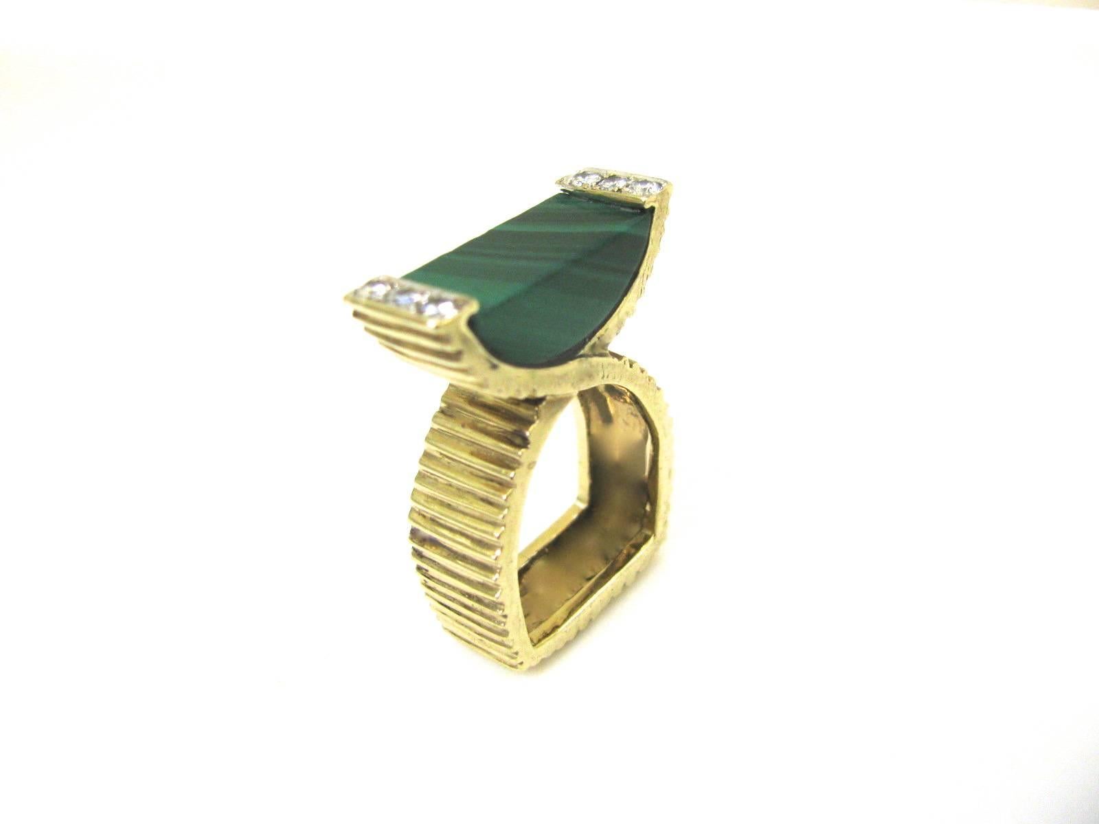 A modernist cocktail ring by La Triomphe. The 14k Yellow gold crossover ribbed shank with malachite flanked by .25cts of round white diamonds.
Very pretty on . Elegant and Unusual.