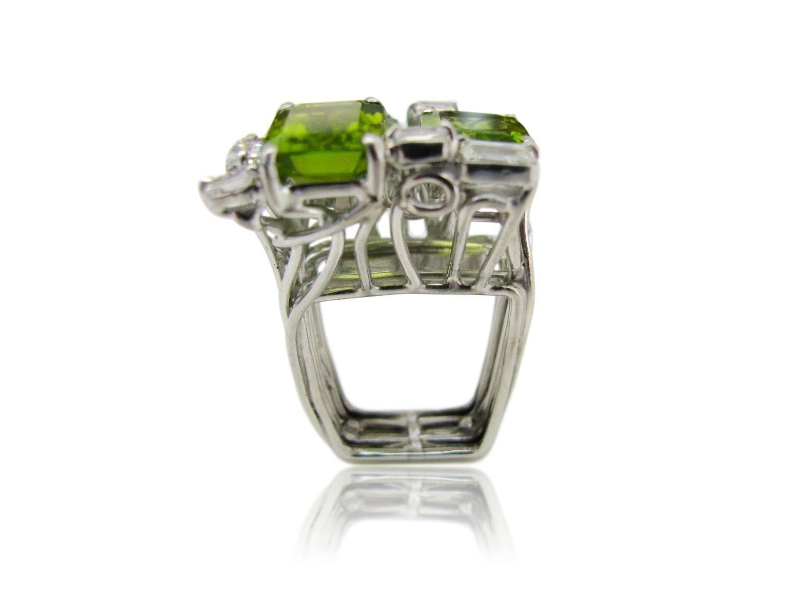 Peridot ring by Barbara Anton. The Platinum mount with a square shank supporting three emerald cut bright apple-green peridot enhanced with numerous white mixed cut diamonds. This one of a kind jewel is designed by Barbara Anton, a Jacqueline of