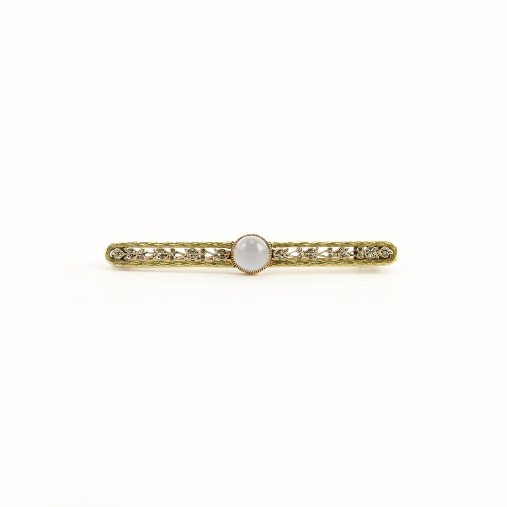 A Fabergé two-color gold, moonstone, and diamond brooch, Moscow, 1908-1917. The oblong bar brooch centered with a cabochon sugarloaf moonstone flanked by rose diamond-set floral bands within a chased green gold laurel leaf border, struck with
