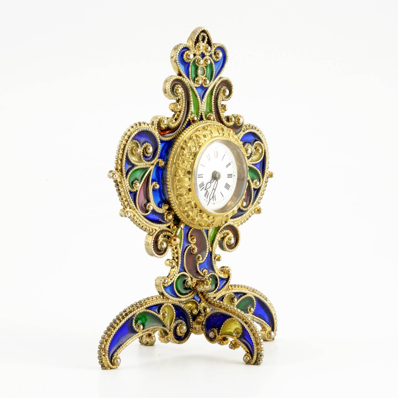 An unusual Austrian silver gilt and plique-à-jour enamel desk clock, Georg Adam Scheid, Vienna, circa 1900. The clock with white opaque enamel dial, black and red Roman Arabic chapter numerals, and pierced black hands, the gilded silver bezel cast