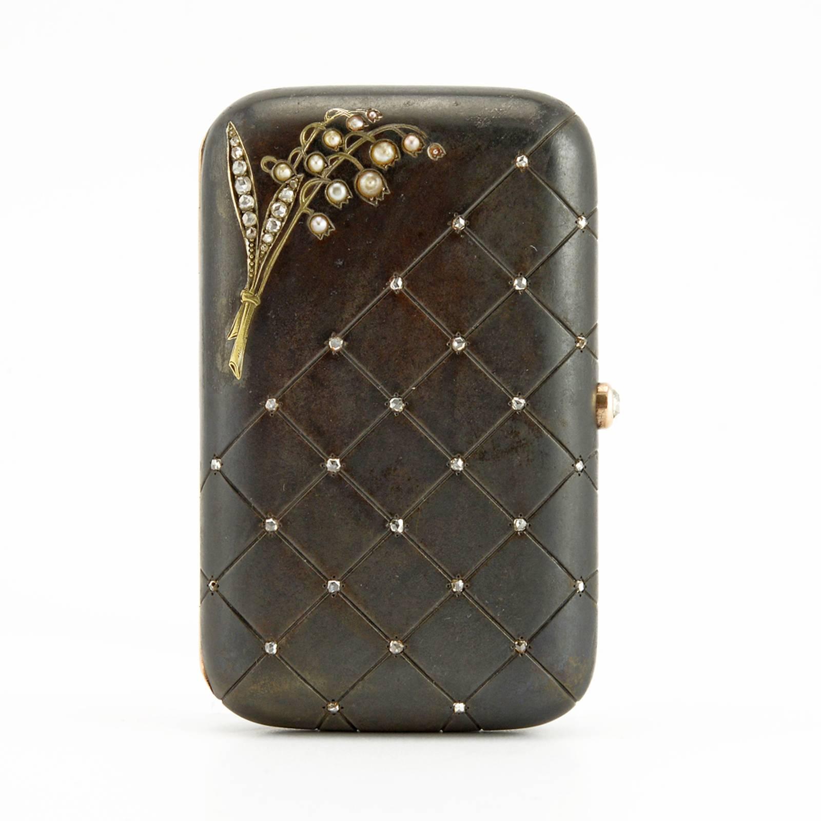 A Russian jeweled gold-mounted gunmetal cigarette case, circa 1900, apparently unmarked but almost certainly by Imperial Court Jeweler Bolin (see references below). Rounded rectangular, both of the hinged covers partially engraved in a net pattern