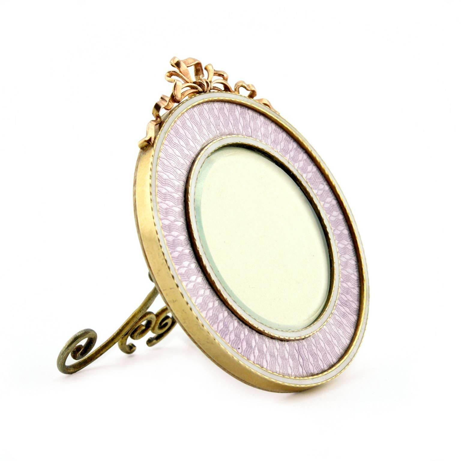 A Fabergé gold and mauve guilloché enamel photograph frame, Moscow, 1899-1908, with original Fabergé scratched inventory number 25205. Of circular form, enameled in translucent mauve enamel over a radiating engine-turned ground within a thin band of