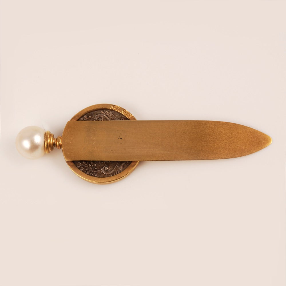 A Faberge 56 standard gold book mark/letter opener, workmaster Erik Kollin, ST Petersburg, circa 1890.  The handle decorated with a Catherine II ruble with a pearl finial.  Length: 2 1/3