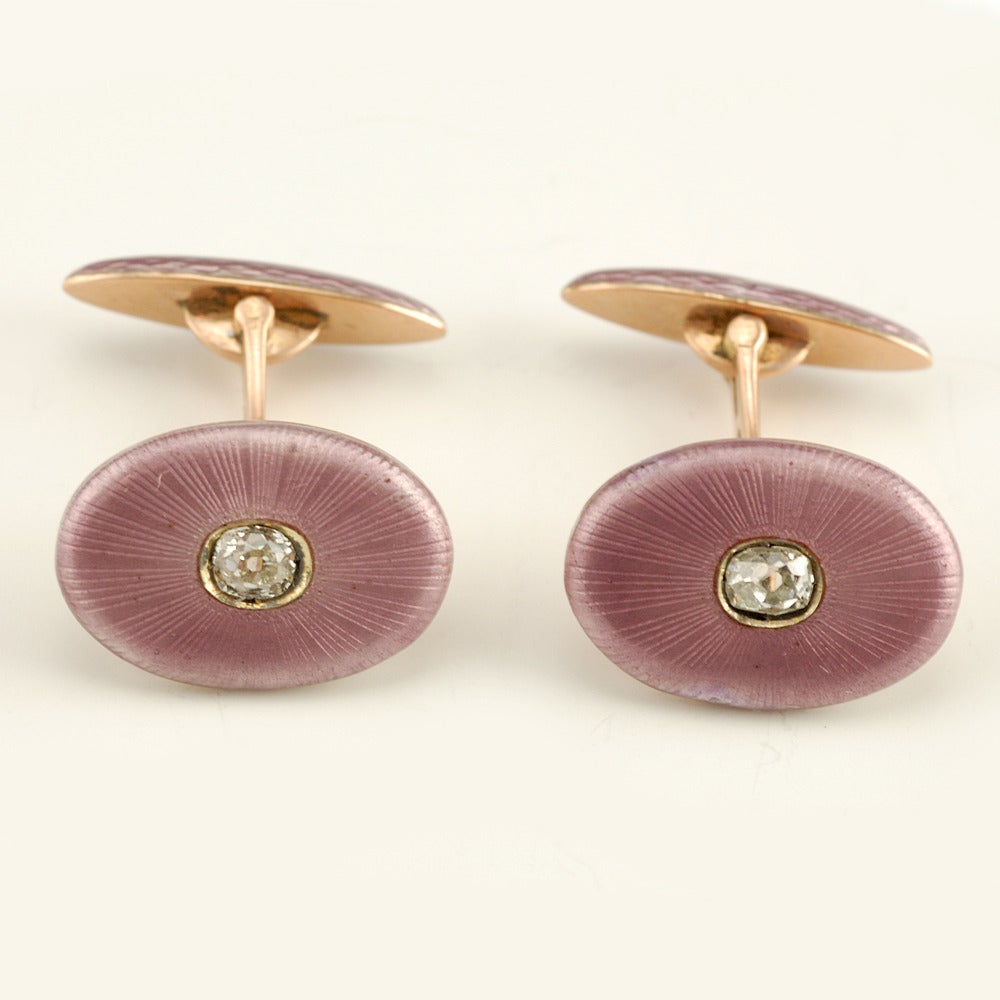 A pair of Russian diamond-set gold and guilloché enamel cufflinks, Andrei Adler, Saint Petersburg, 1908-17, contained in their original fitted box of the retailer Alexander Treiden. Each oval link enameled lavender over a sunburst engined-turned