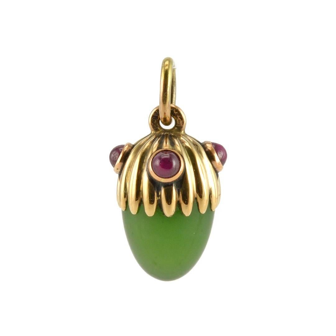 A Fabergé gem-set gold and carved nephrite miniature pendant Easter egg, Saint Petersburg, circa 1895. The carved nephrite with a fluted gold cap-form mount with collet-set cabochon rubies. Height ¾ in. (1.9 cm).